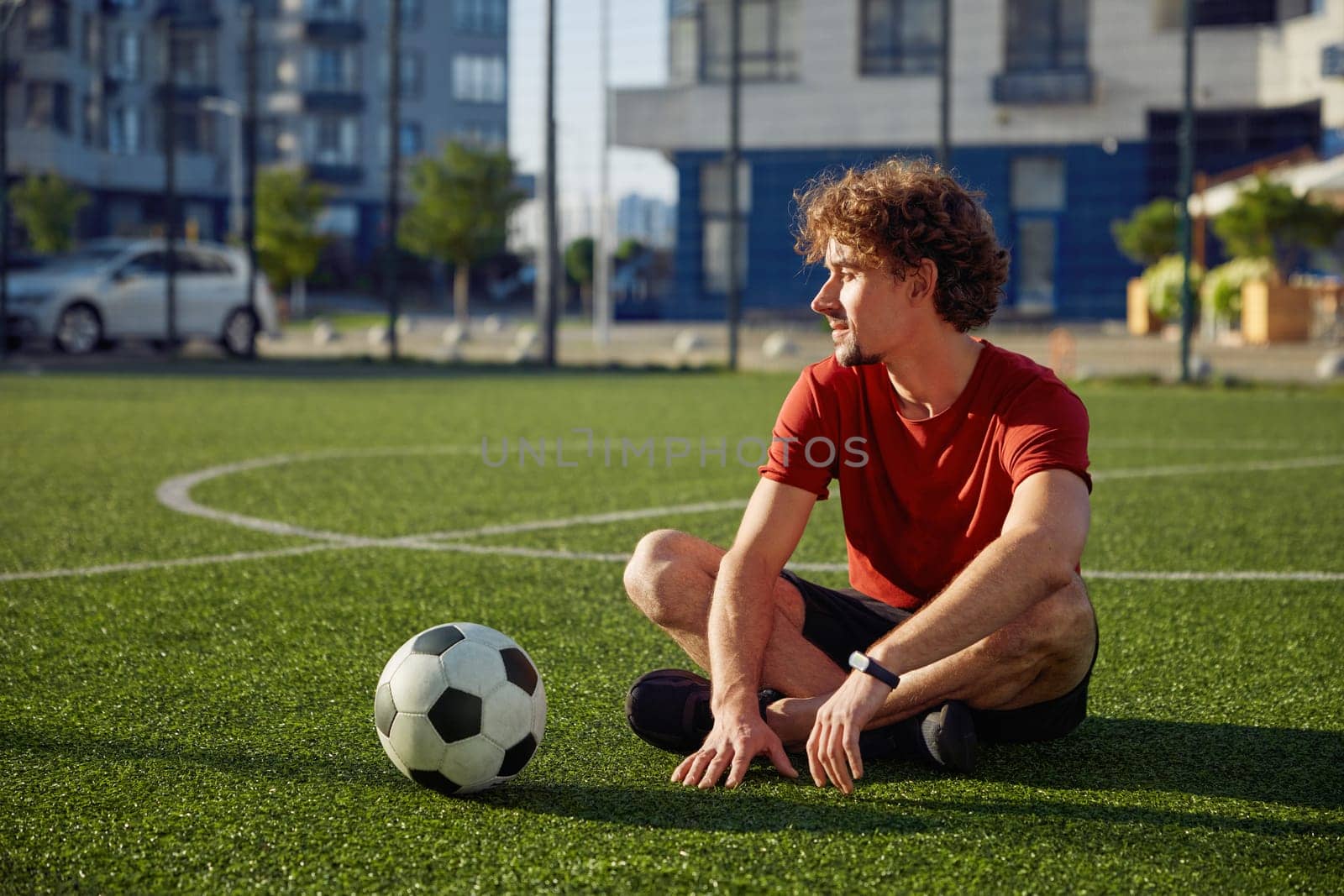 Restful father sitting on football stadium grass dreaming and relax
