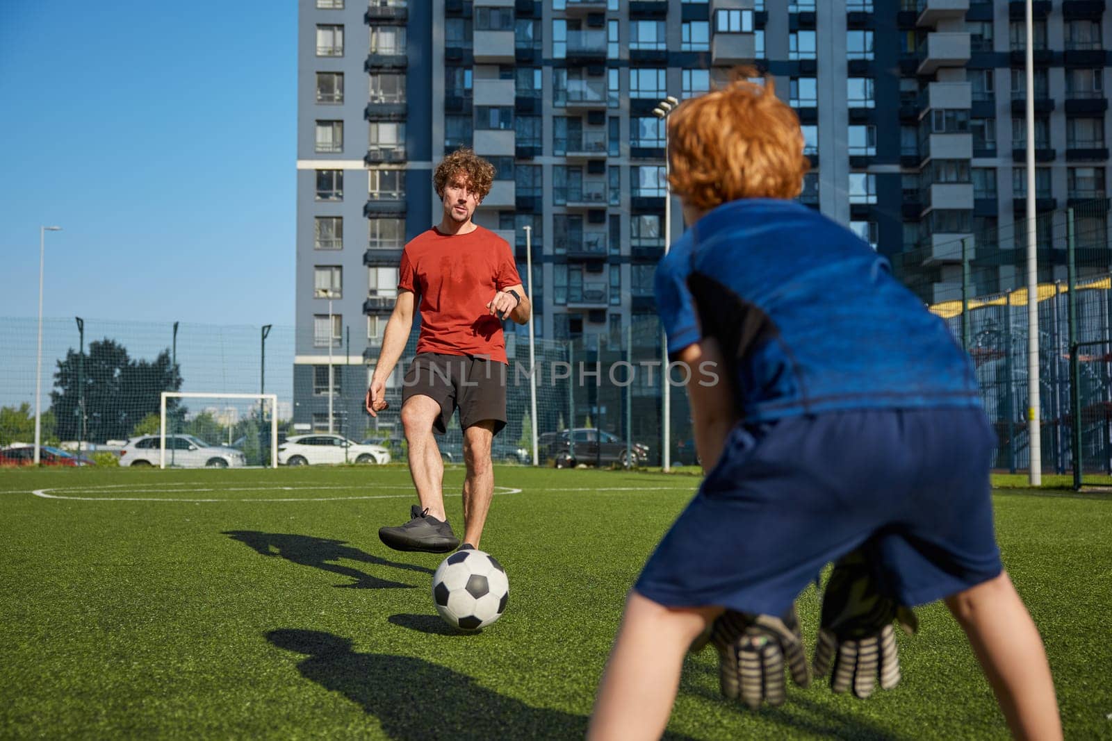 Dad with his little cute son playing football practicing game at city stadium. Active family and soccer sport
