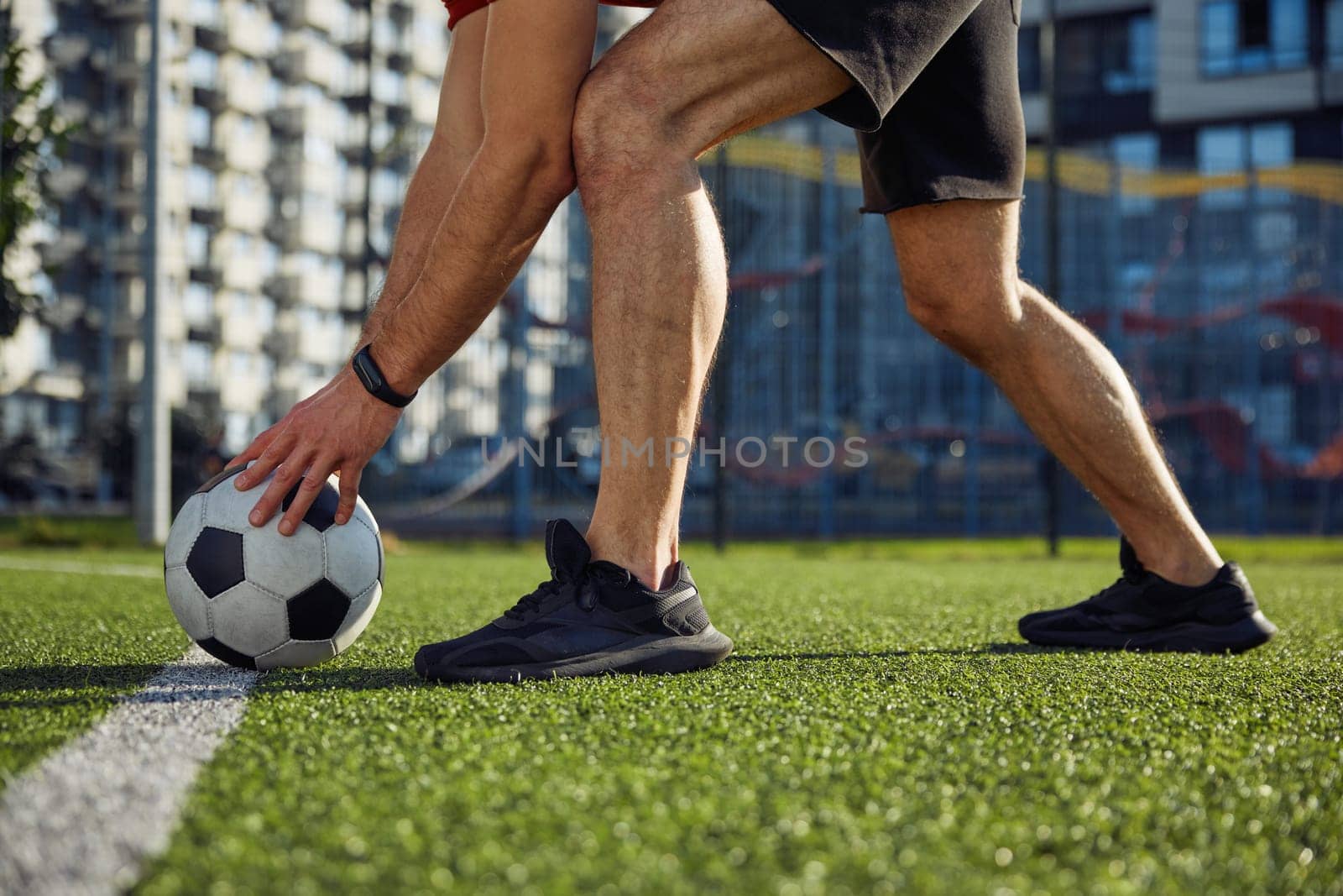 Start football match. Male player putting ball on strip line on center of soccer field cropped closeup shot