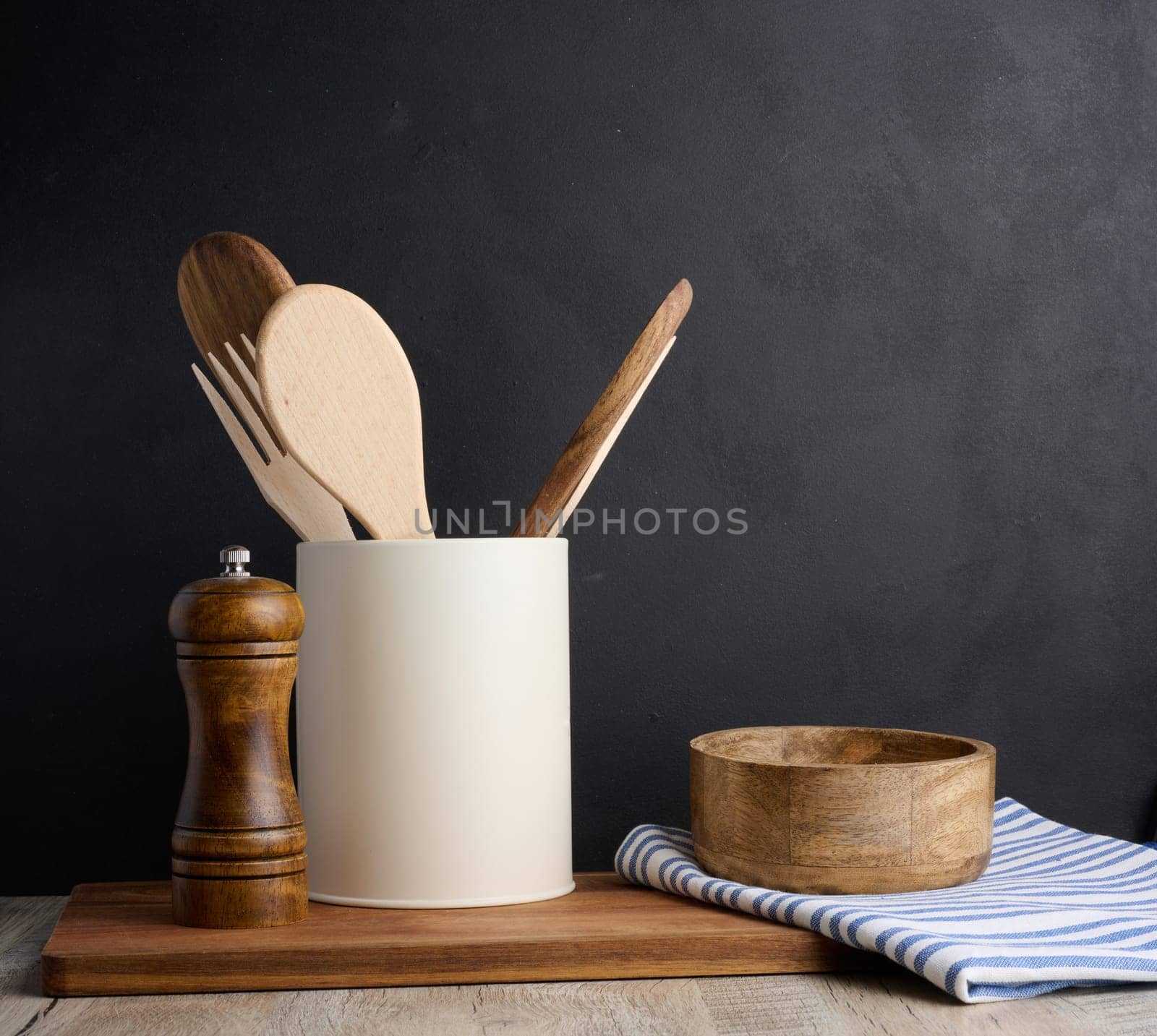 Empty bowl and wooden spoons on a table, black background