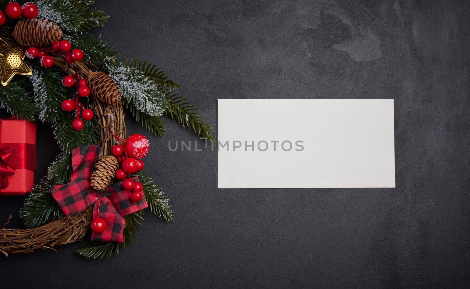 White envelope and Christmas wreath on a black background, top view