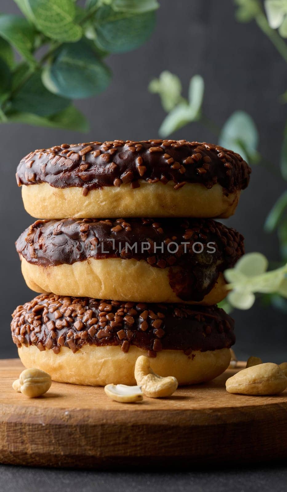 Chocolate donuts sprinkled with crushed nuts on a black table
