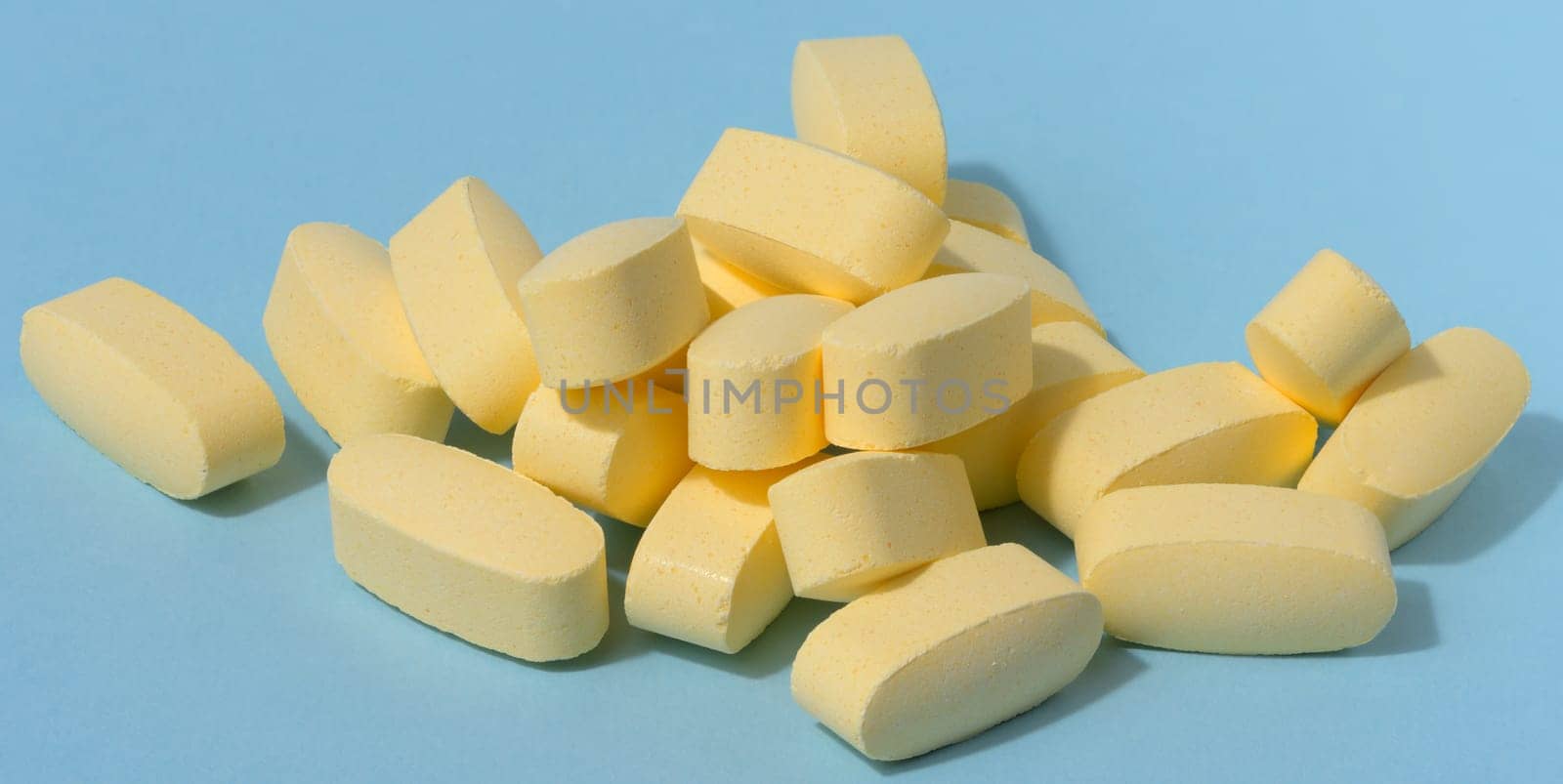 Yellow oval tablets on a blue background, close up