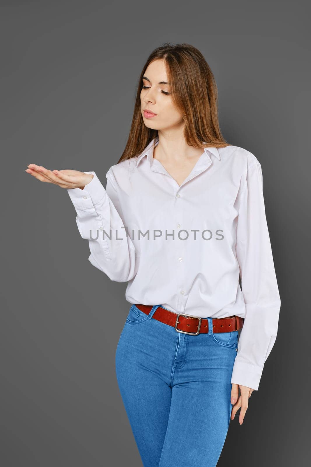 Cute woman stretched her hand forward with her palm up and looks at it with an interest