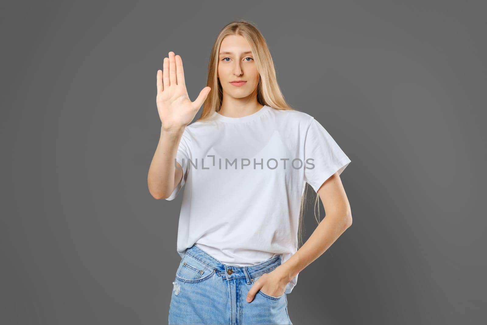 Serious young woman puts her palm forward in a stopping gesture