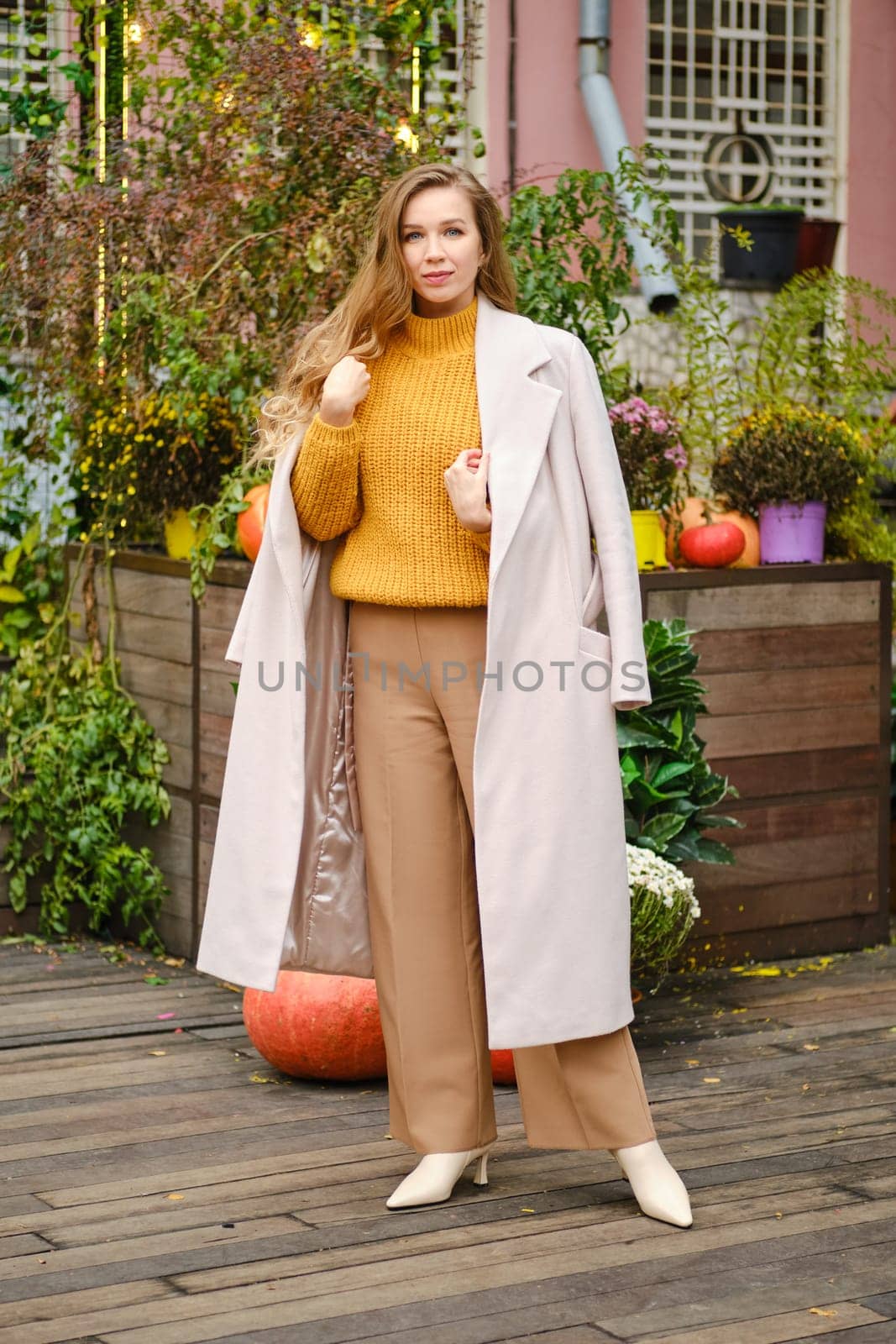 Outdoor autumn portrait of young fashionable woman wearing beige coat and loose trousers