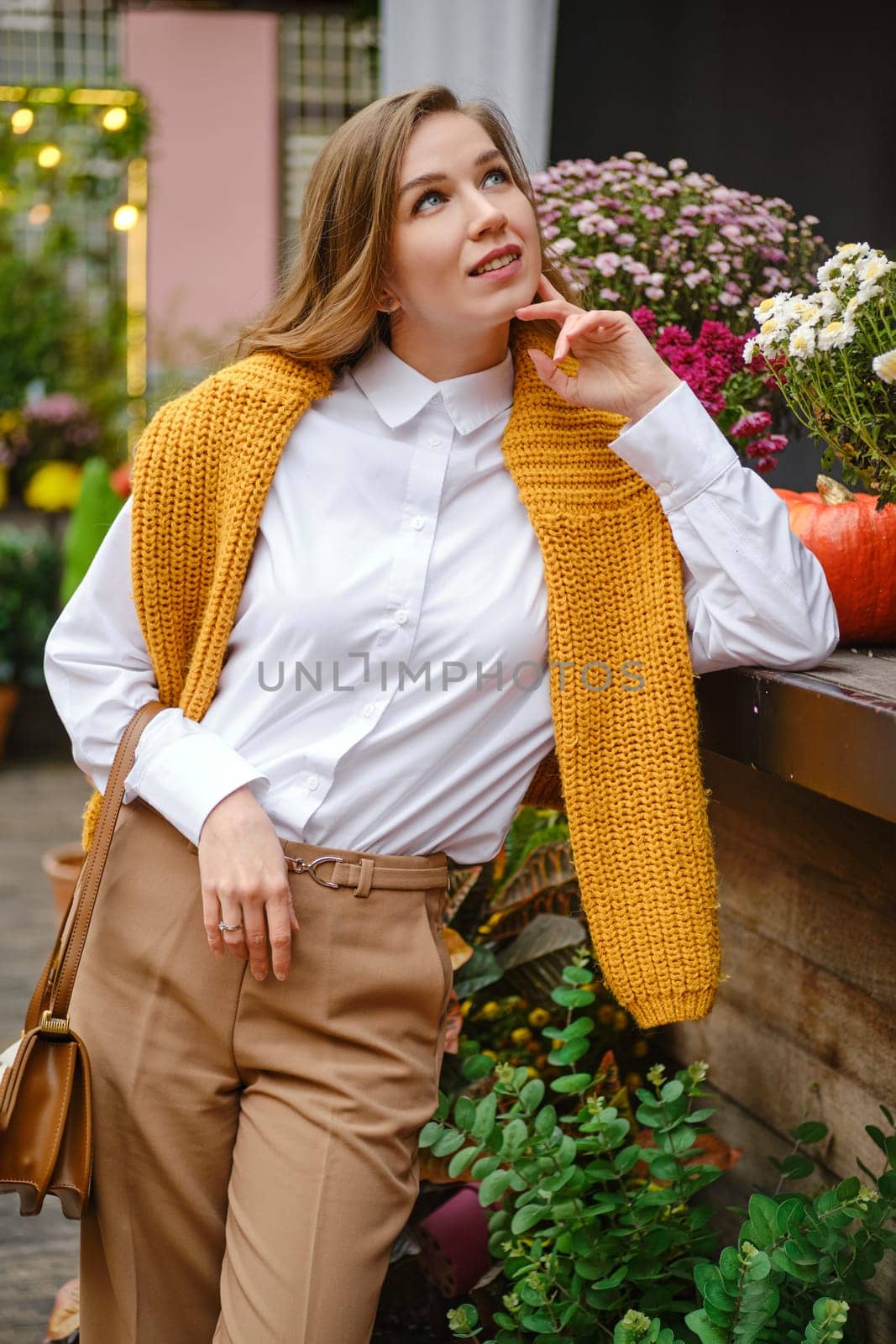 A dreamy woman stands among autumn plants and looks up