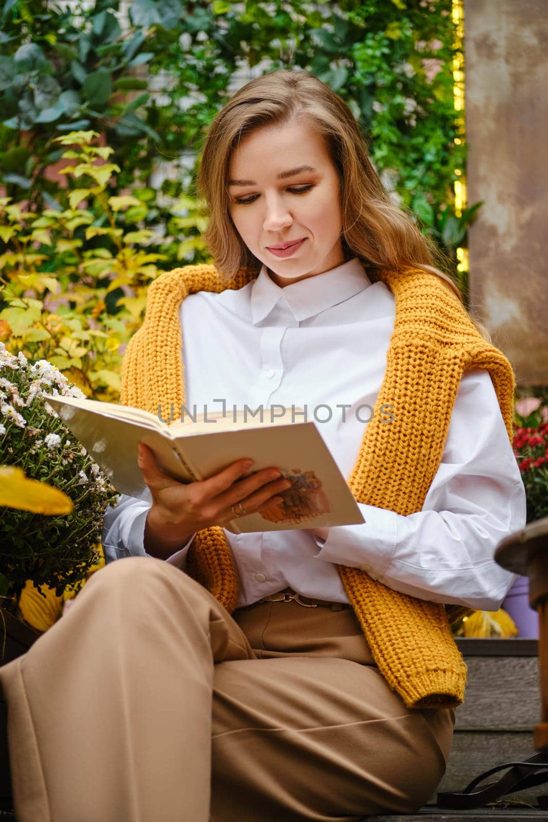 Cute woman sitting on bench and read a book in warm autumn day