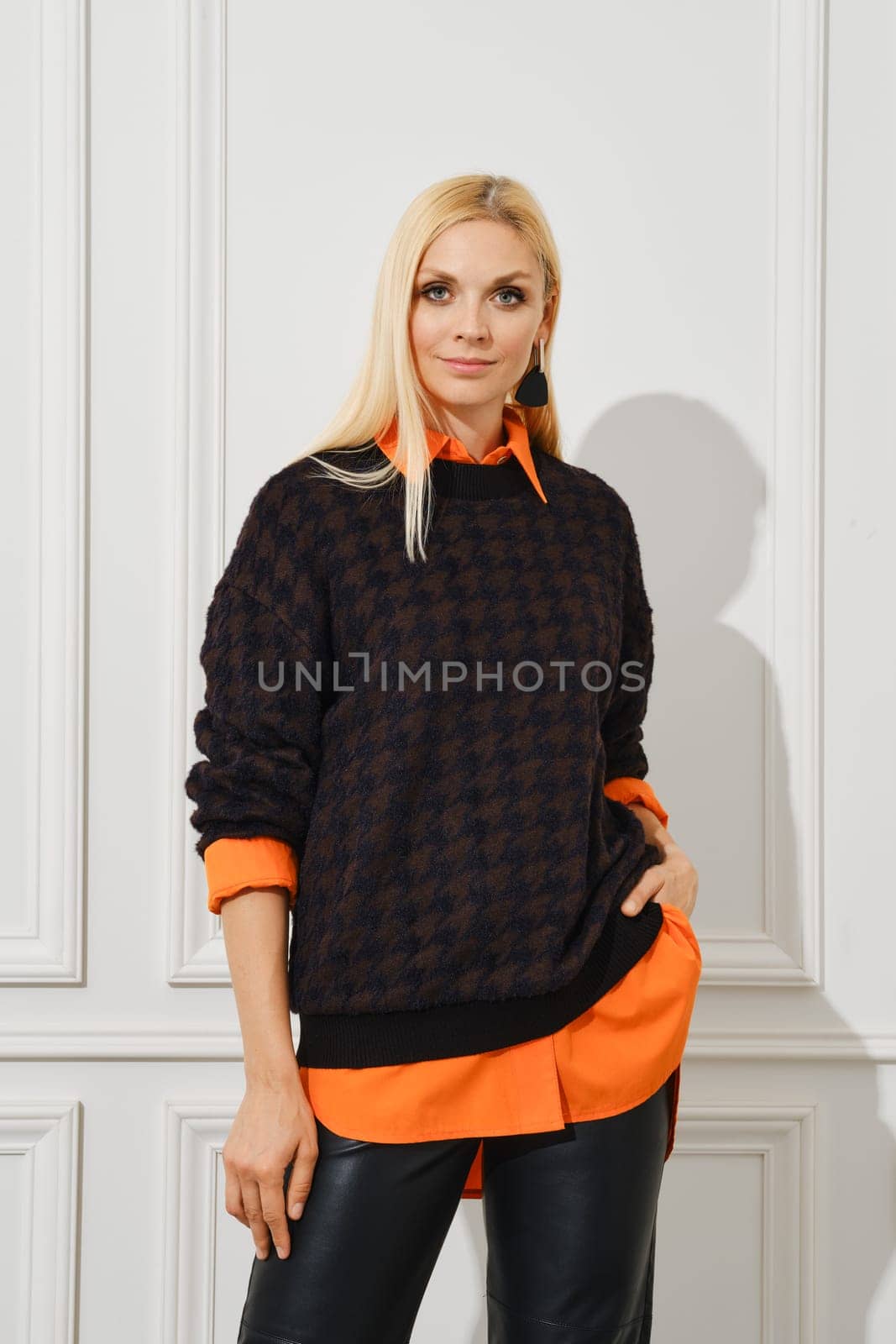 Casual portrait of woman in leather pants and a shirt sticking out from under a sweater