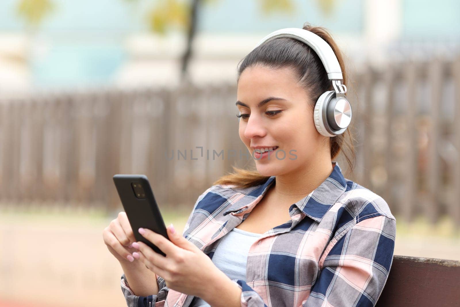 Happy teen listening music in a bench