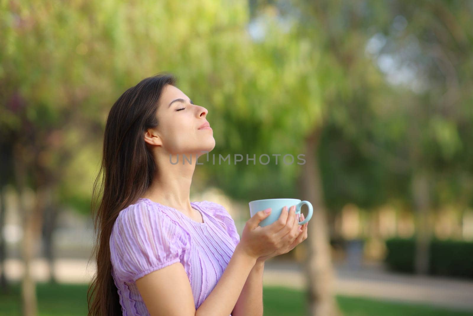Profile of a woman breathing drinking coffee in a green park