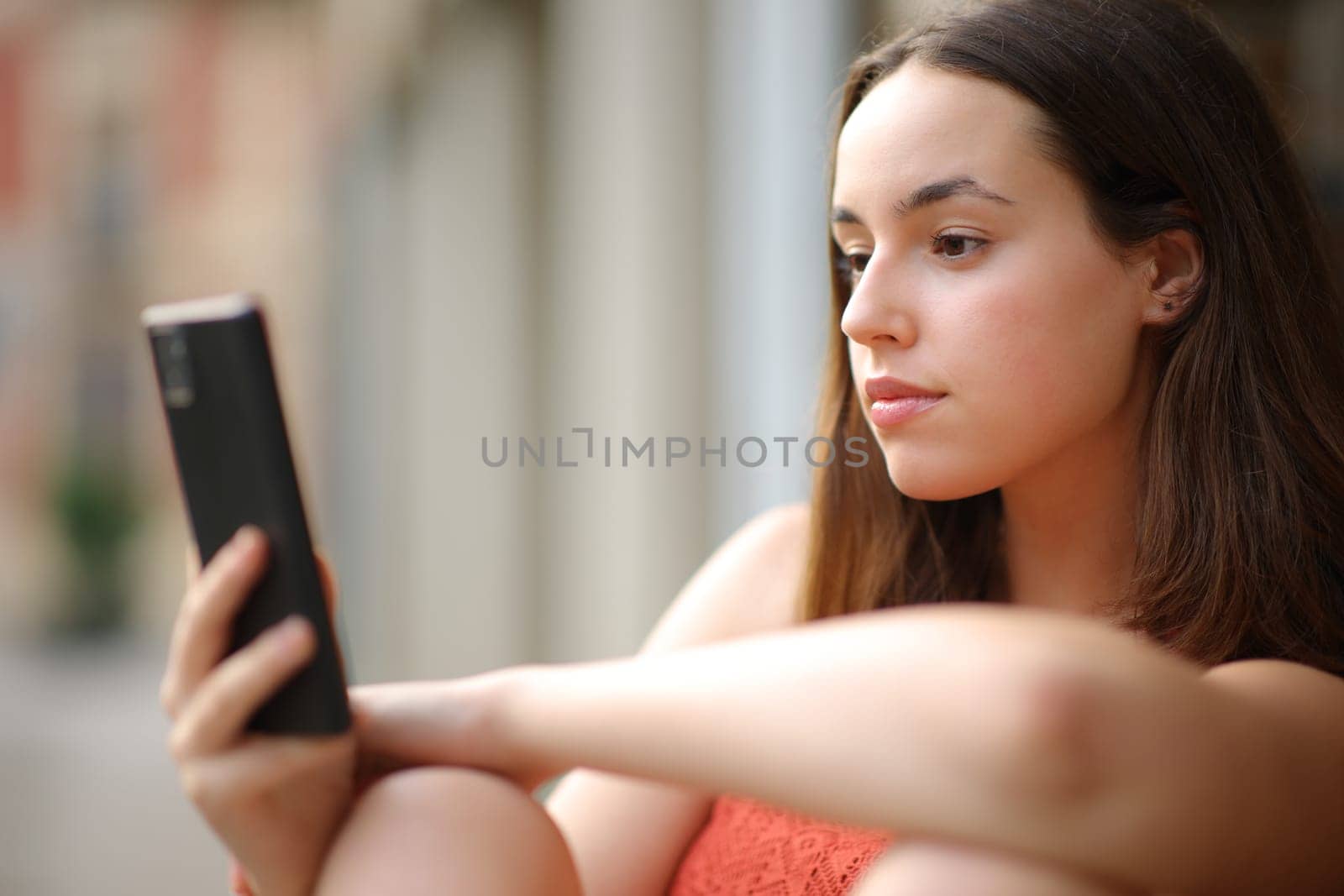 Serious woman checking phone content outdoors in the street