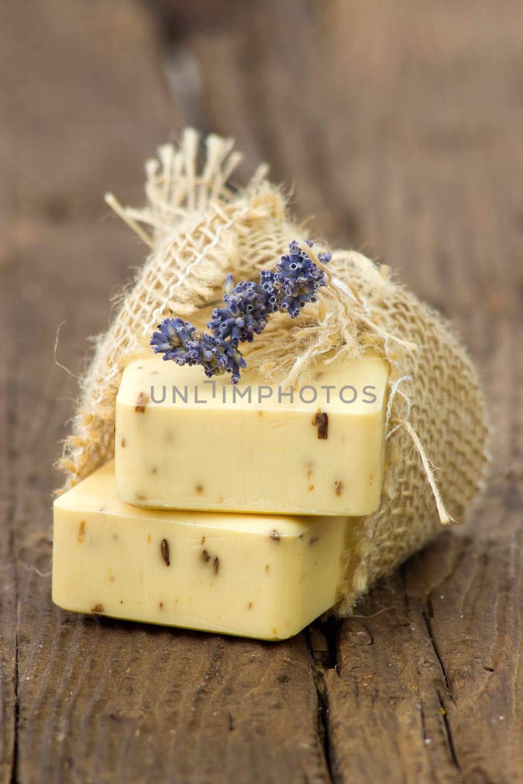 bar of natural soap with dried lavenderon wooden background