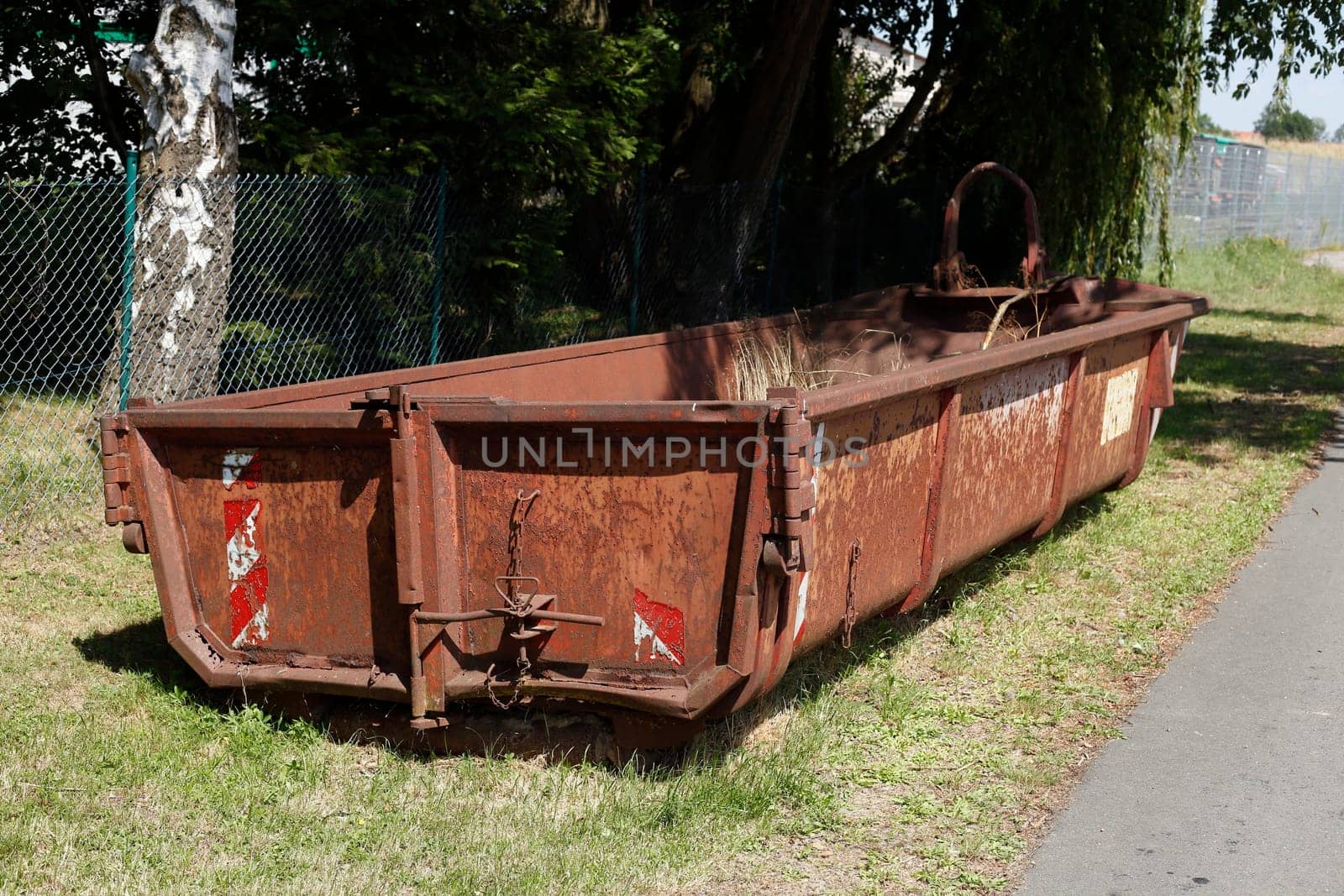 Old brown dumpster with plant waste standing on a meadow, Germany, Europe