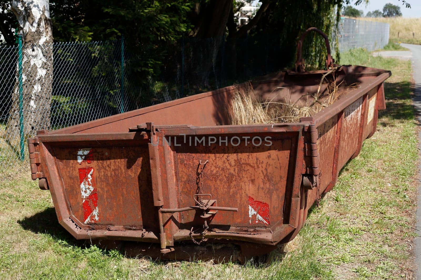 Old brown dumpster with plant waste standing on a meadow, Germany, Europe