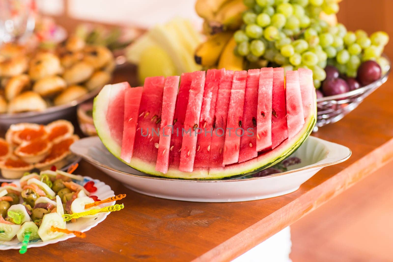 Sliced watermelon on a dish. Sweet berry on the table. The pink flesh of watermelon for dessert. Healthy food for vegetarians. Festive table setting with fruit and berries.