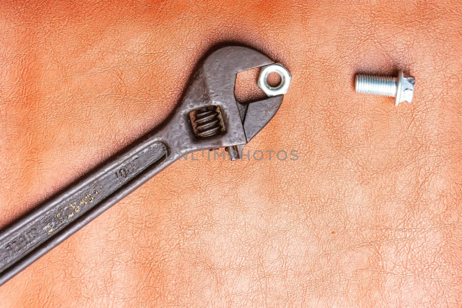 Wrench, hex bolt and hex nut on leather floor.