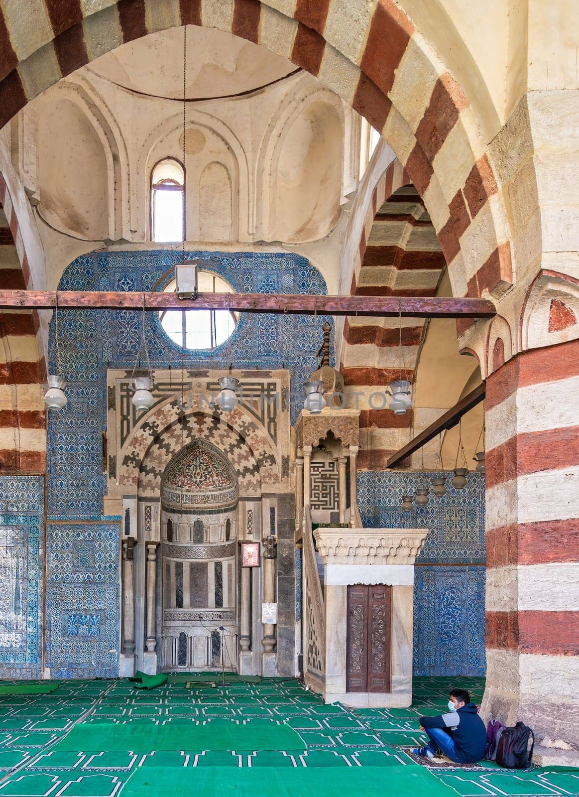 Cairo, Egypt - November 27 2021: Engraved Mihrab, and decorated marble Minbar, in front of blue Iznik ceramic tiles, framed by big arch, at Mamluk era historical Mosque of Aqsunqur -Blue Mosque
