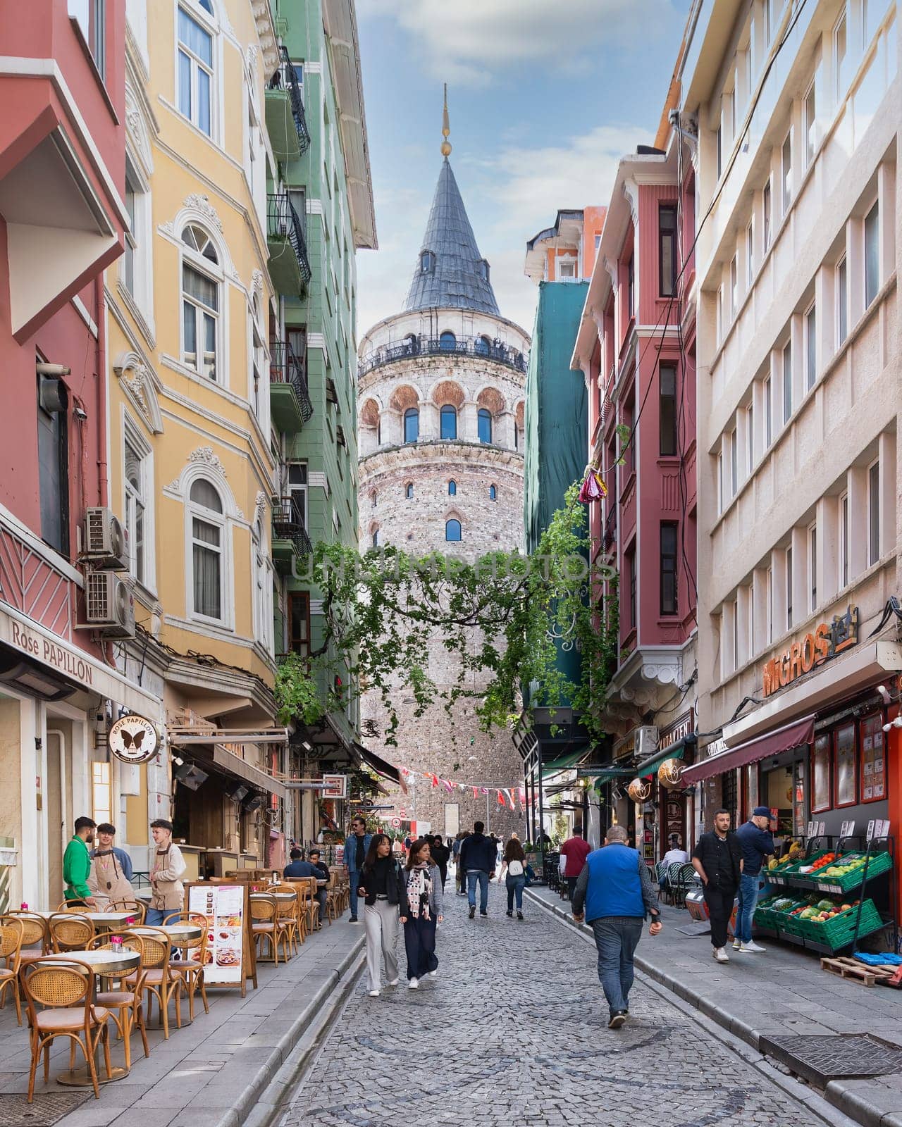 Istanbul, Turkey - May 13, 2023: Popular tourist destination Galata Tower, taken from the narrow and atmospheric cobblestone crowded Buyuk Hendek Street