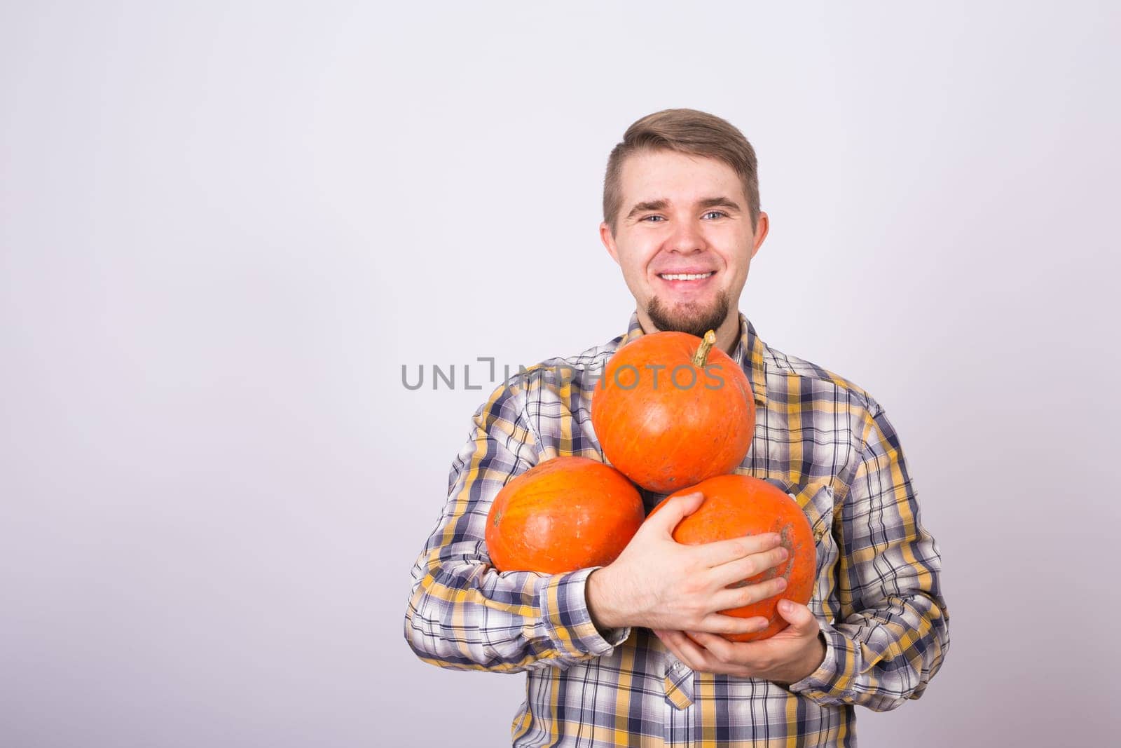 portrait of a young farmer holding a pumpkins on a light background studio.
