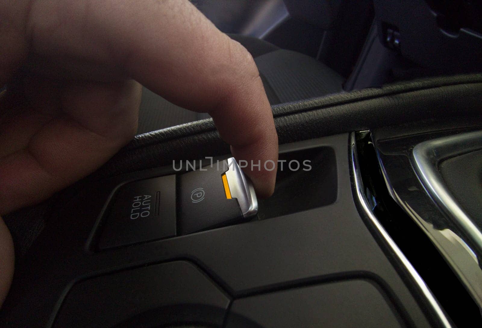 Driver pulling the electric parking brake of his car. Yellow color light indicating brake activation in progress