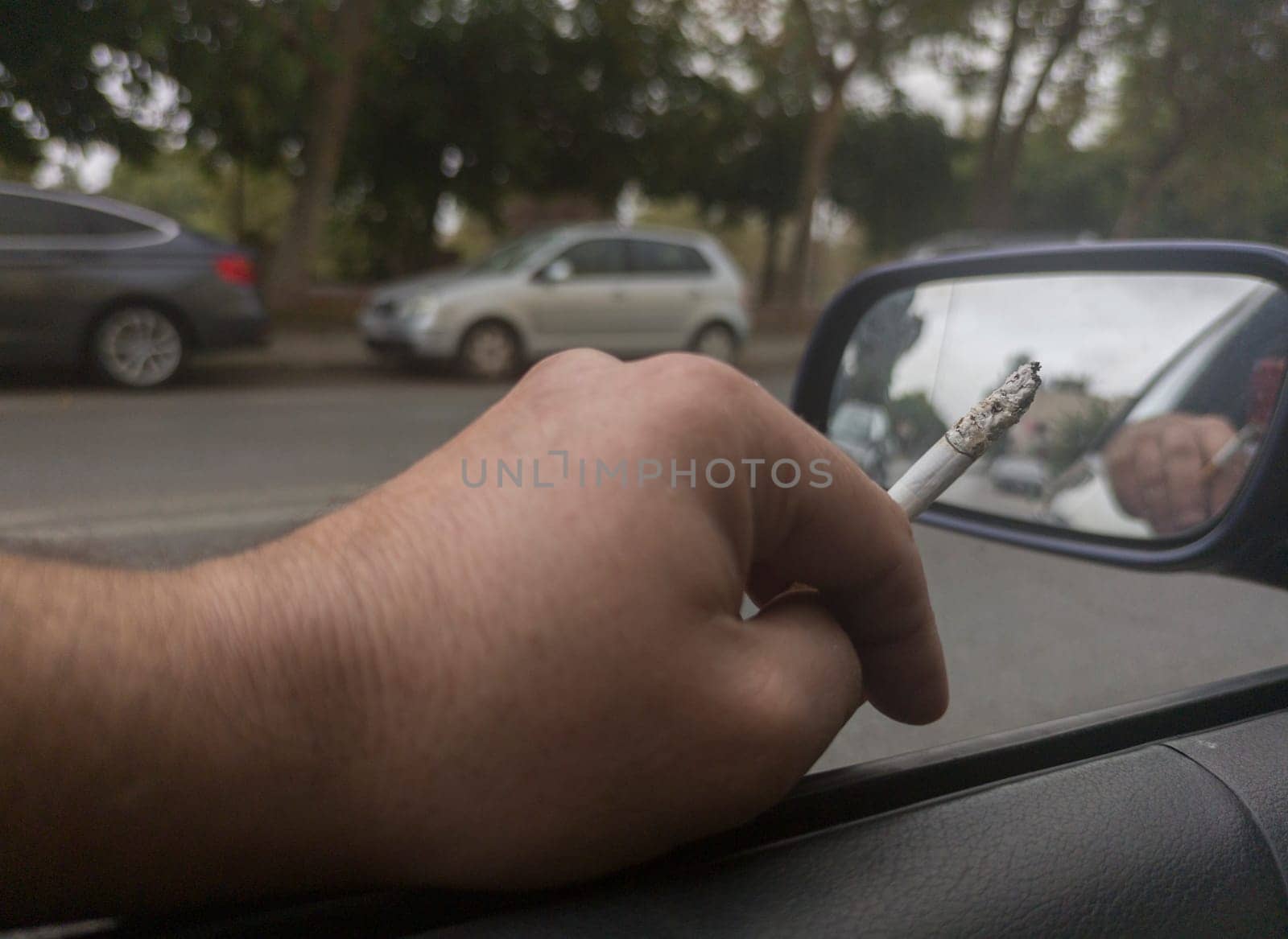 Man smoking and driving with the window down. Cause of distracted driving accidents concept