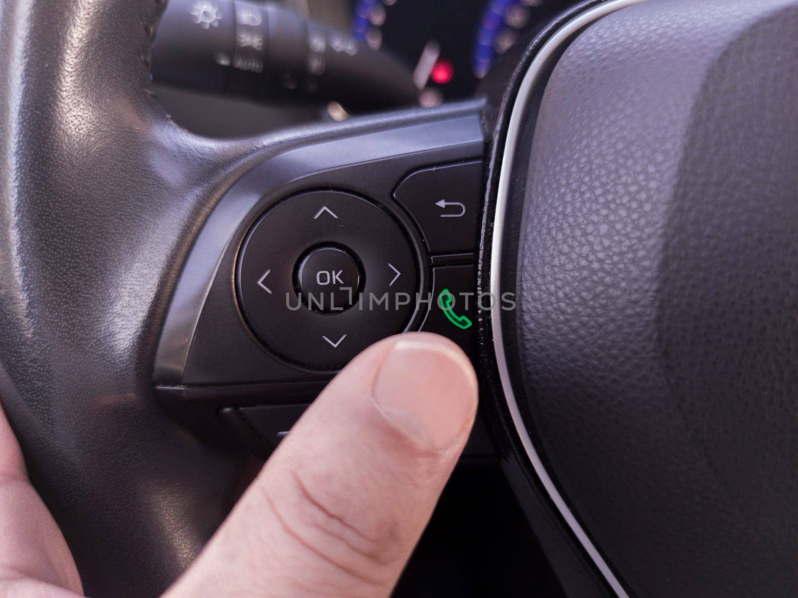 Driver about to pick up the phone from the steering wheel controls
