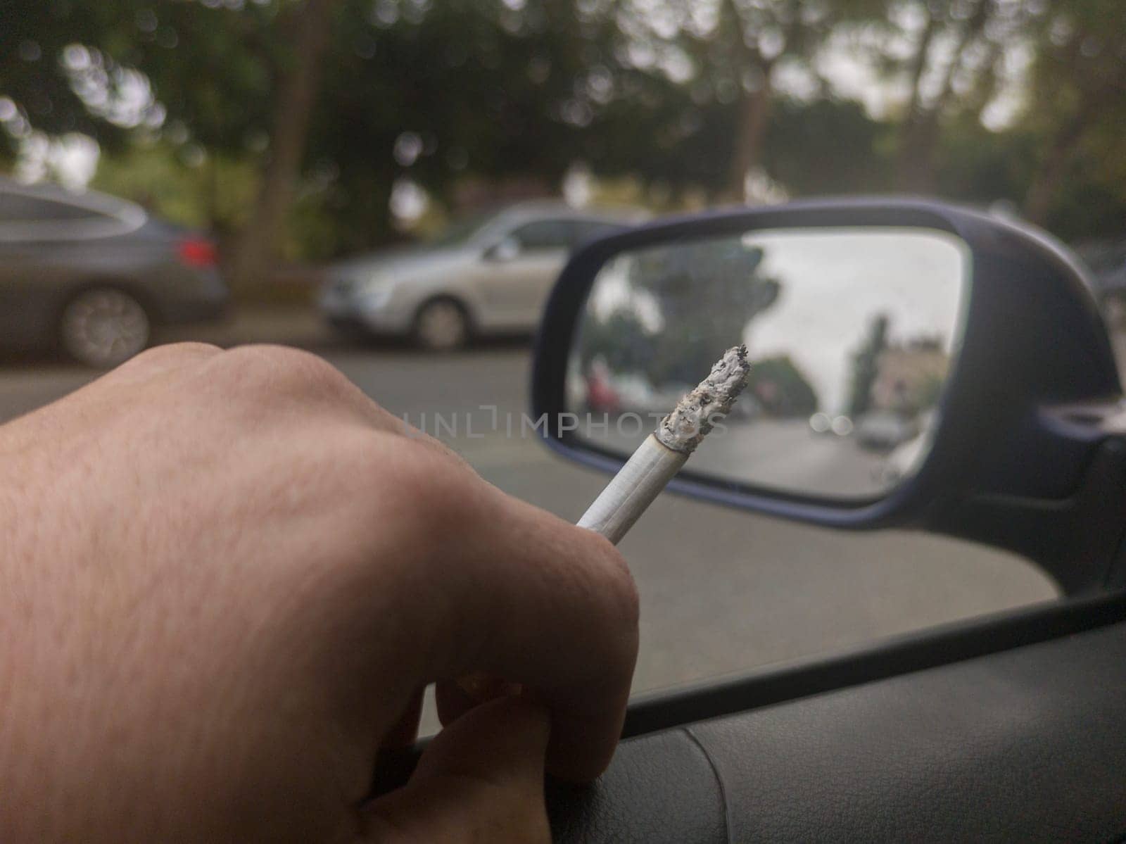 Man smoking and driving with the window down. Cause of distracted driving accidents concept