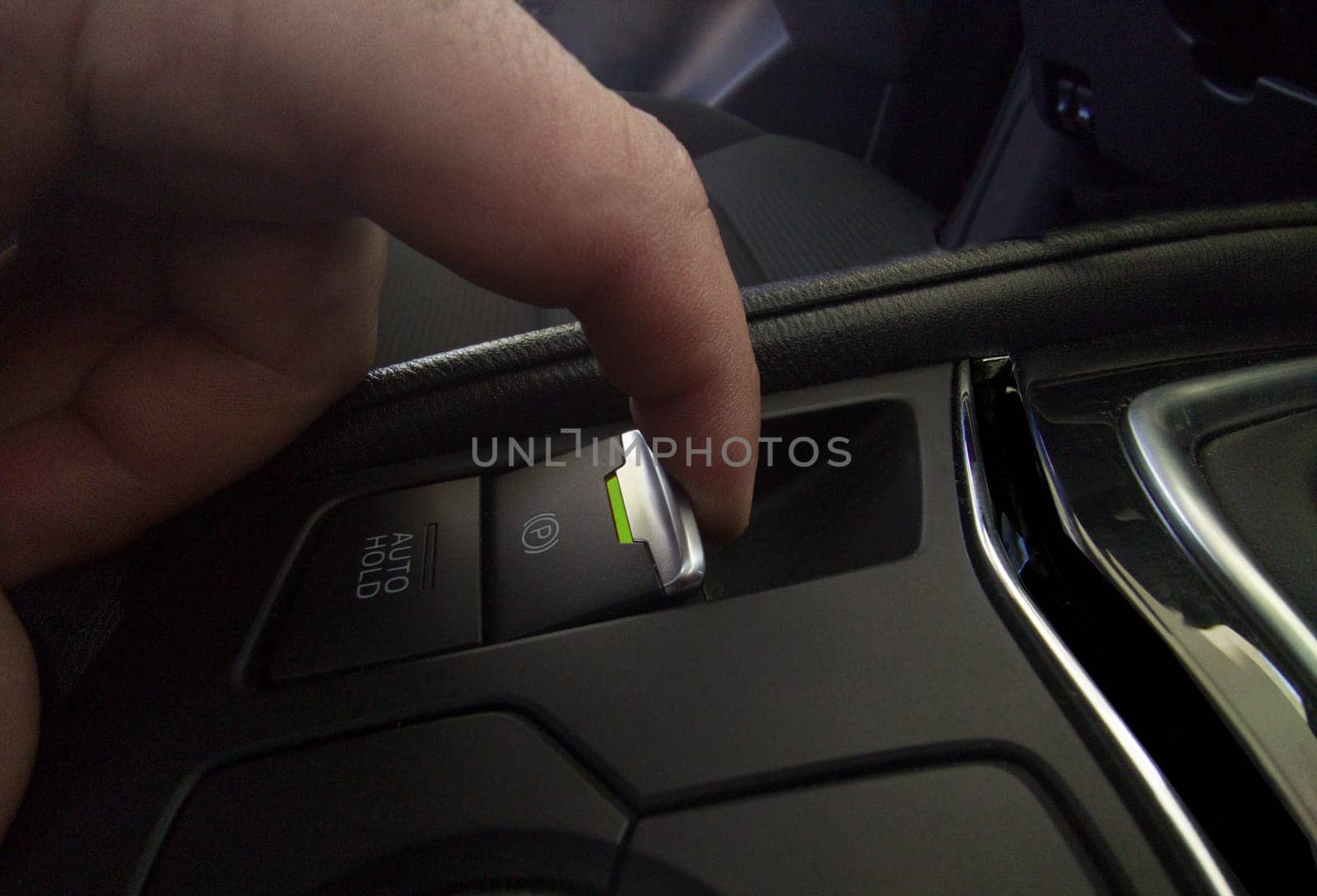 Driver pulling the electric parking brake of his car. Green color light indicating brake activation
