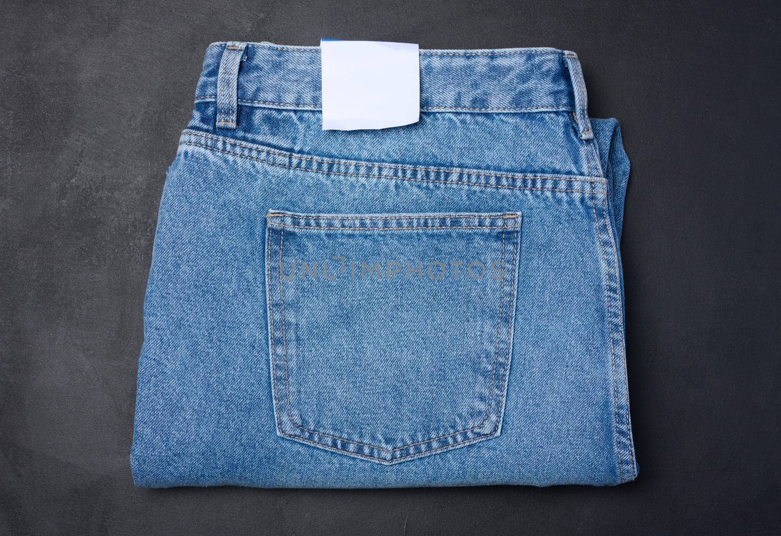 Folded blue jeans on a black background, top view