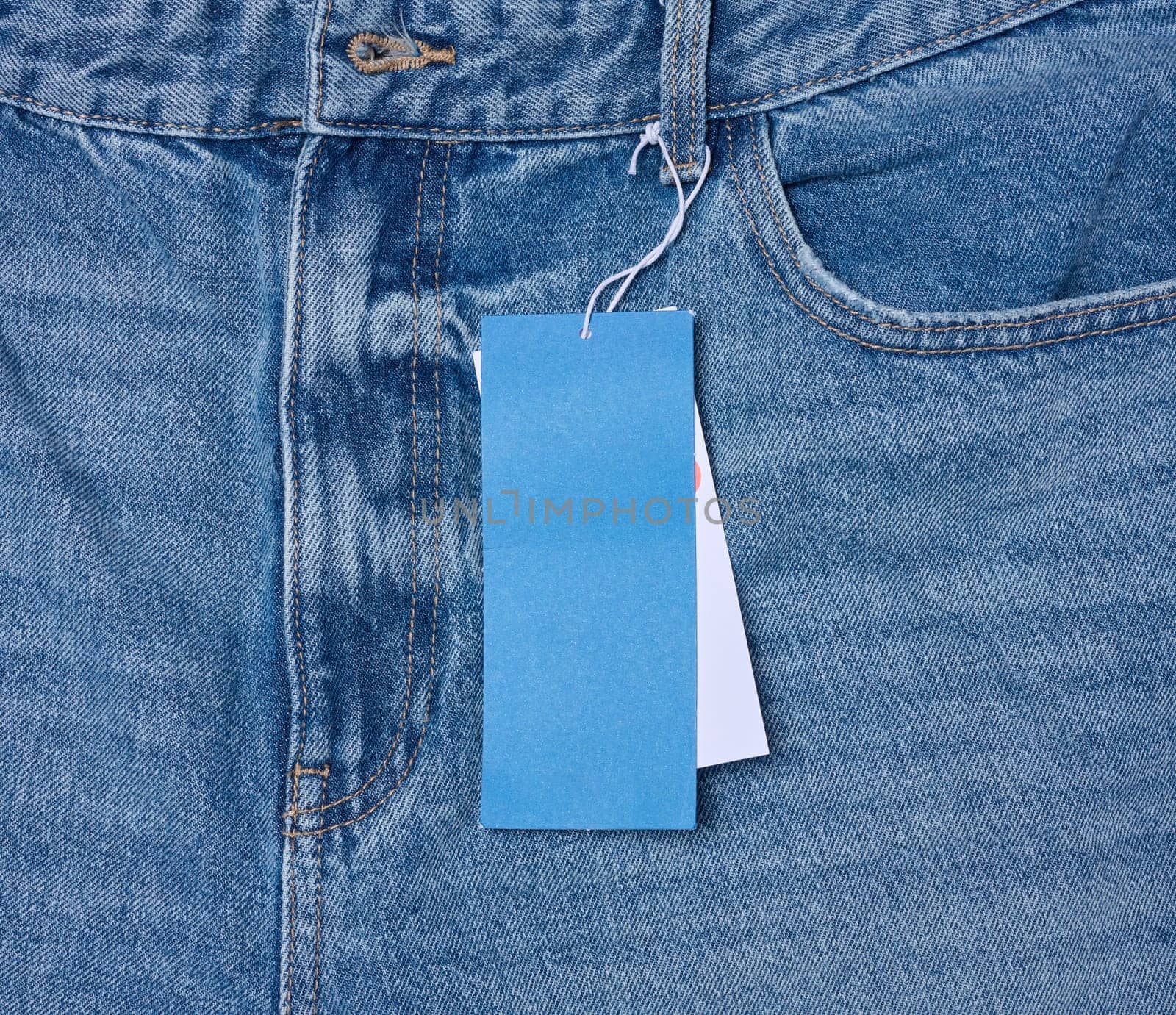 Paper price tag on a rope tied to the waistband of blue jeans