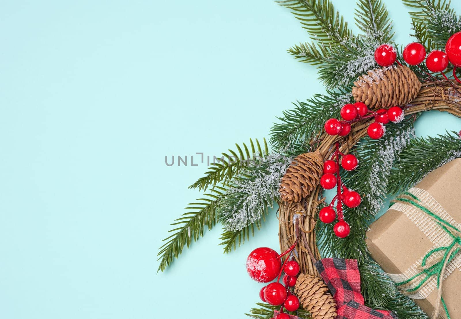 Christmas wreath made of fir branches and other decorations on a blue background, copy space