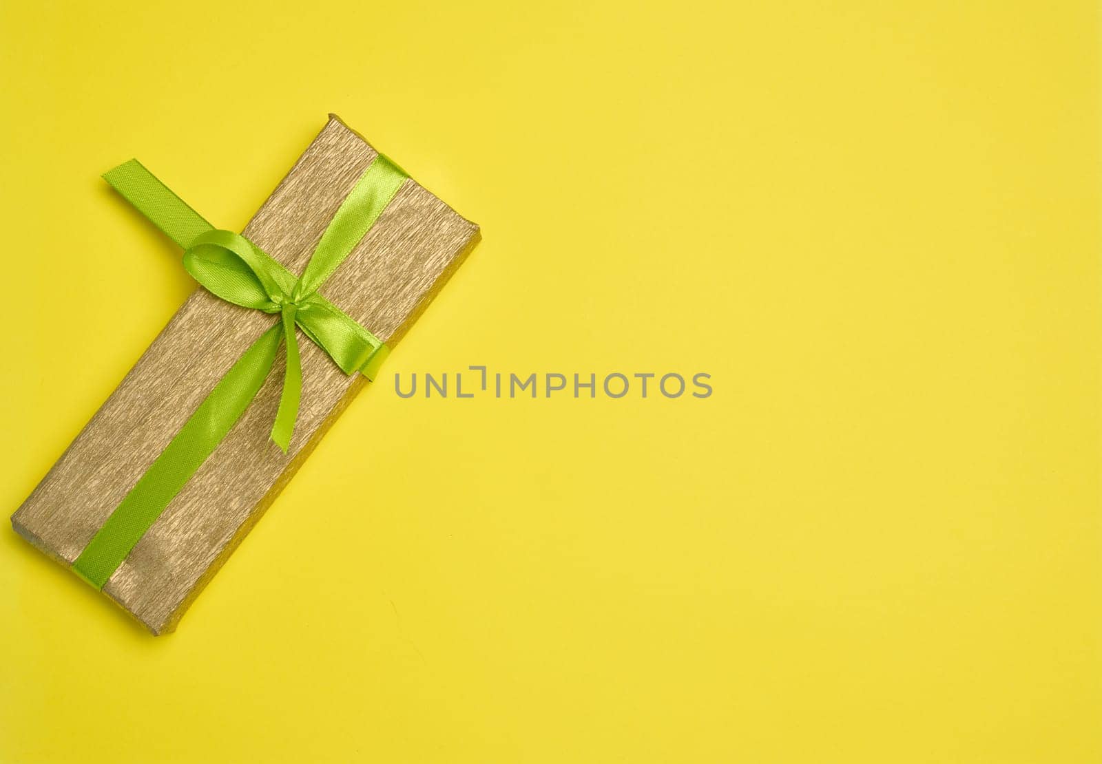 Boxes packed in paper and tied with ribbon on a yellow background, gifts. Copy space