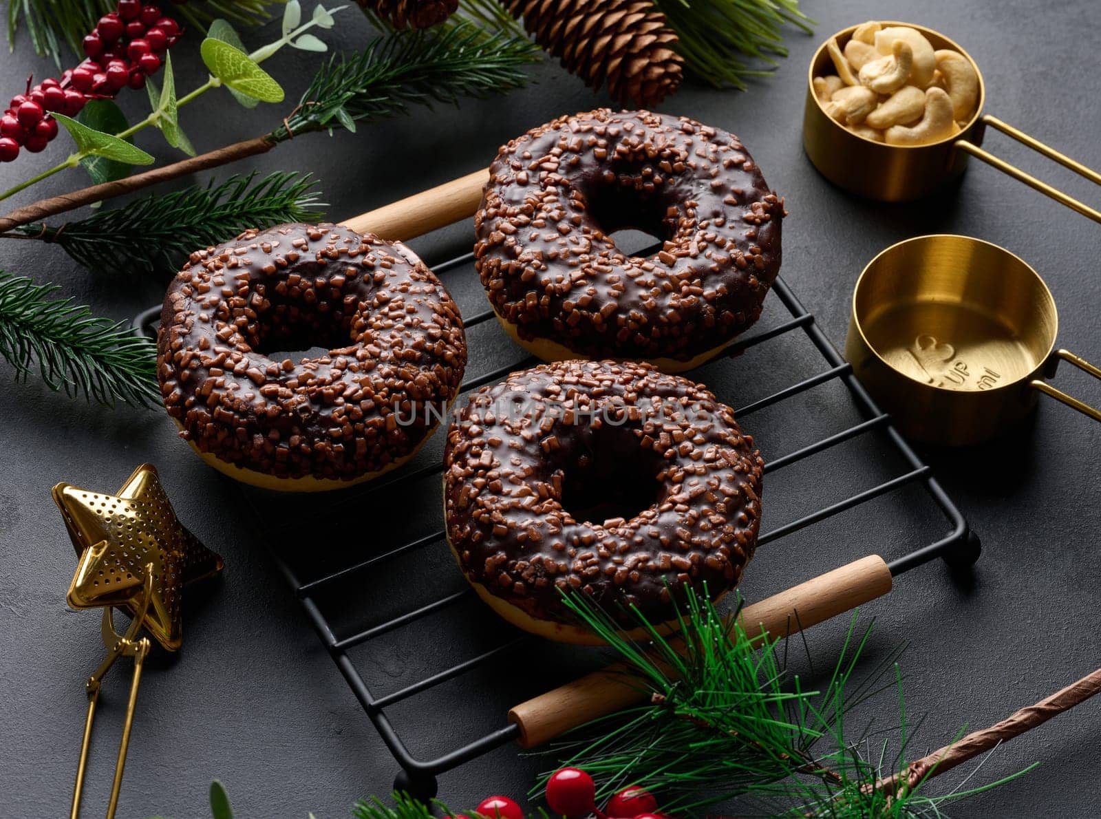 Chocolate donuts sprinkled with crushed nuts on a black table