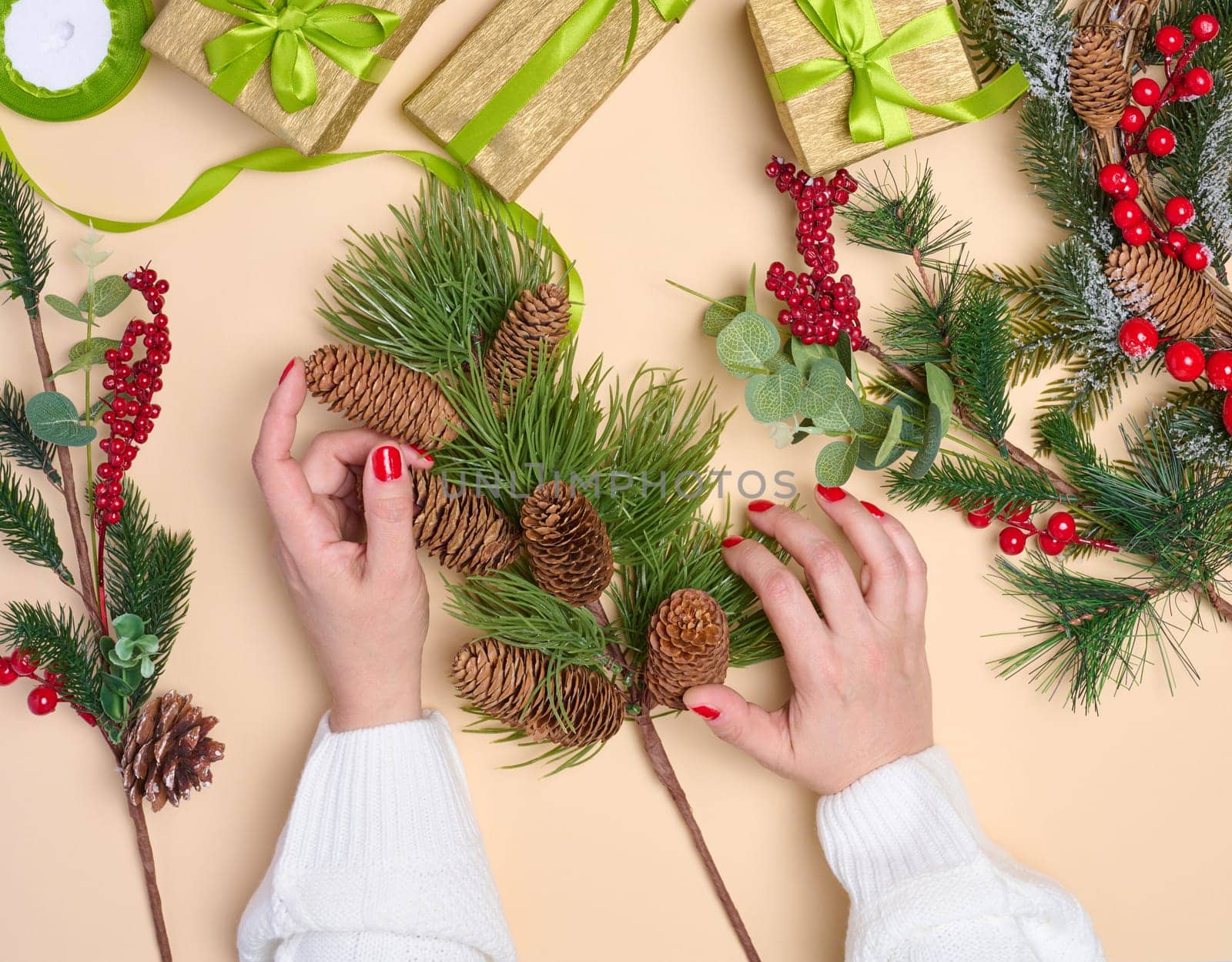 Woman is packing gifts, the pre-holiday bustle and preparations for Christmas. Gifts wrapped in paper and tied with green ribbon are laid out on the table