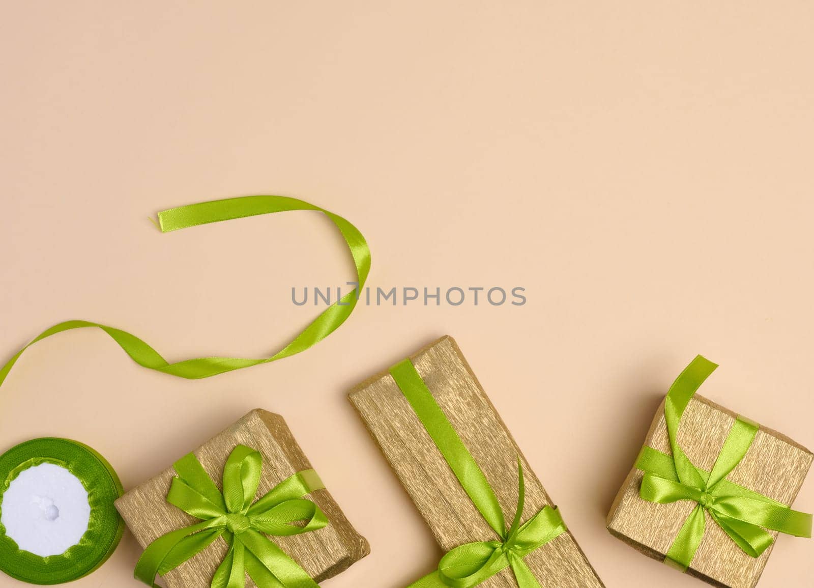 Boxes packed in yellow paper and tied with ribbon on a beige background, gifts