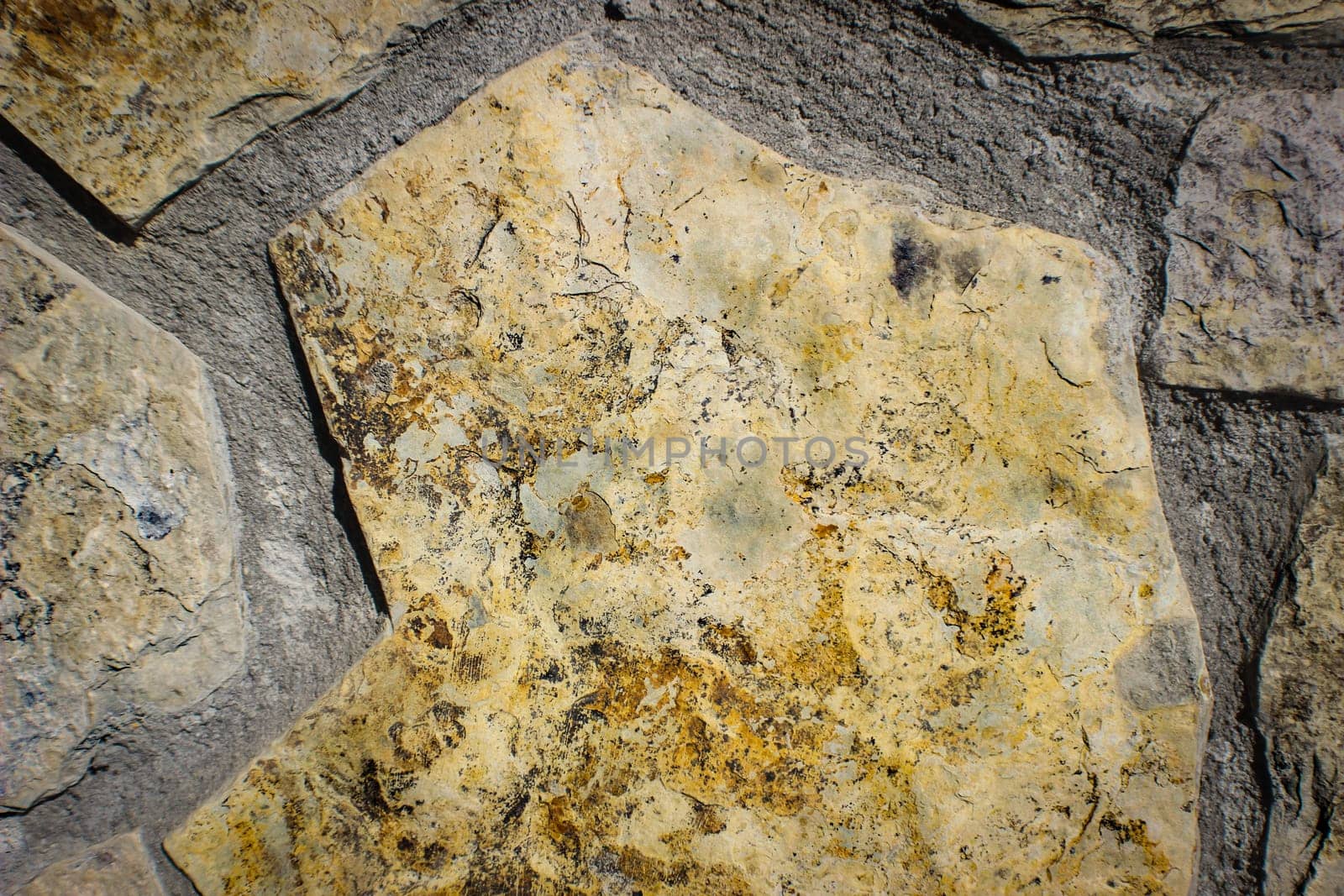The texture of coarse old, ancient brown carved uneven stones, cobblestones with the suture laid on the floor in the bristchatku. The background.