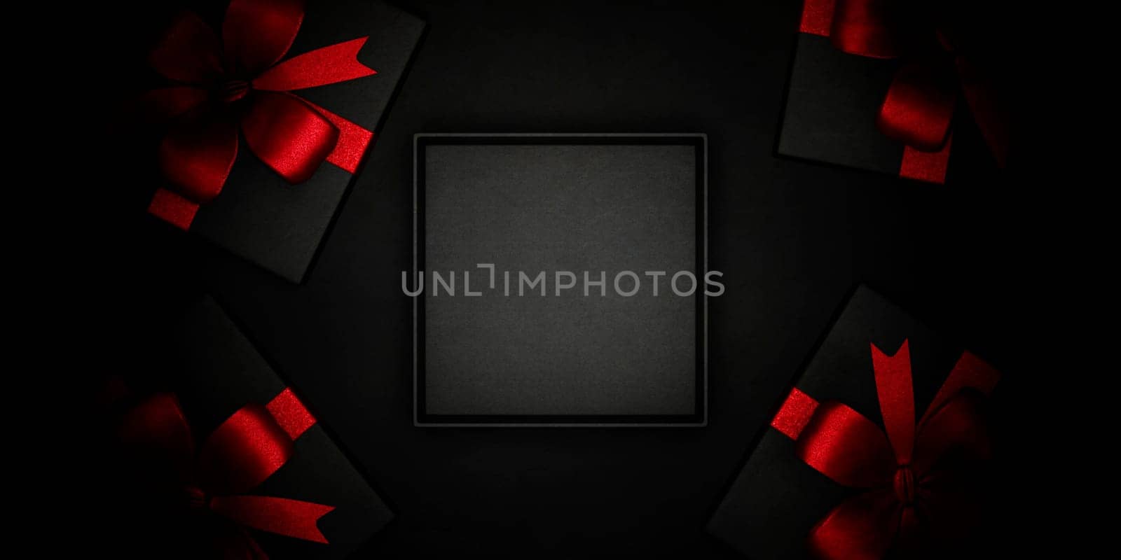 Empty black gift box and present wrapped with red ribbon from above. Black friday, christmas and new year holiday background scene. Luxury premium product placement mockup.