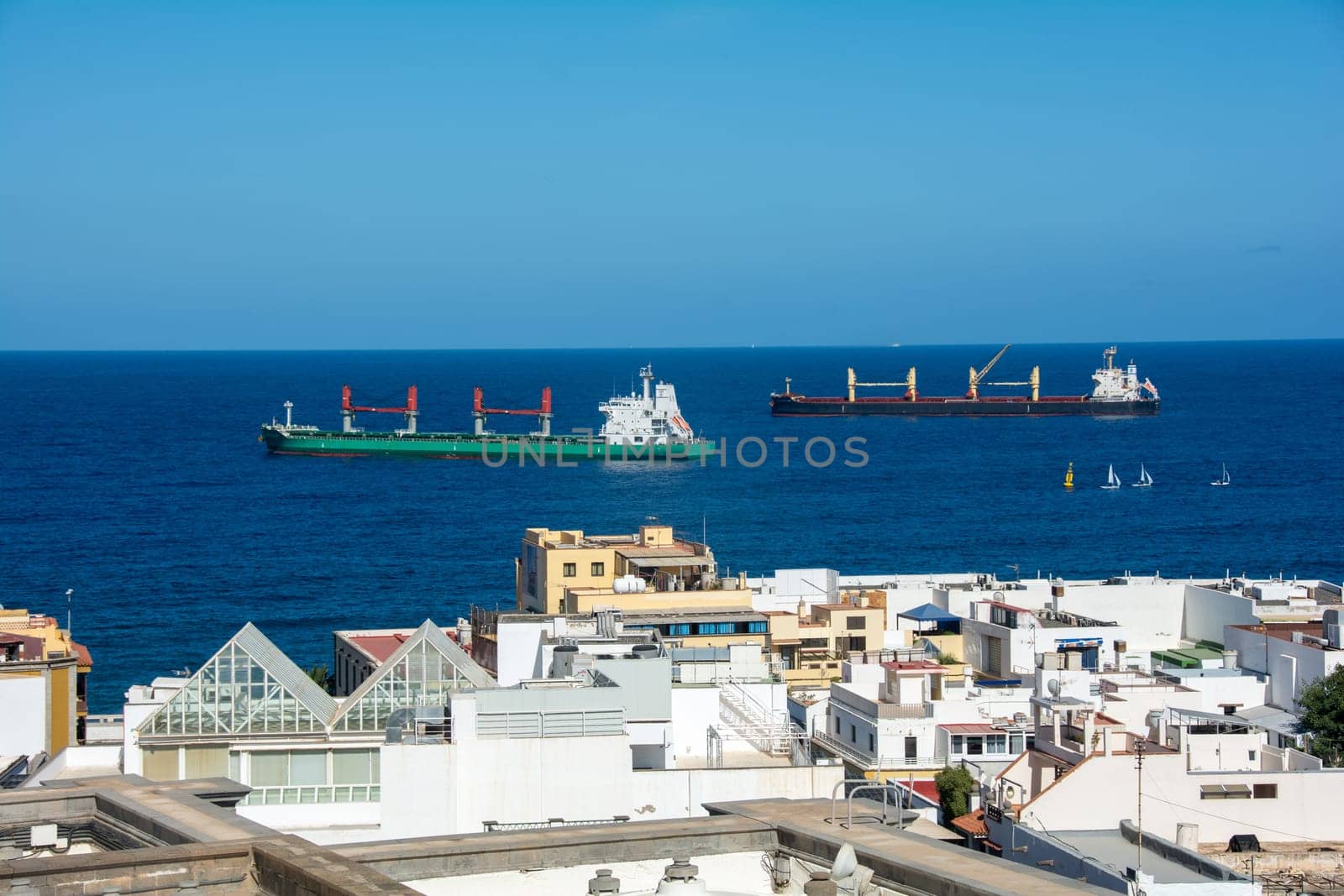 Freighter in the sea with roofs of the city of Las Palmas Gran Canaria, Spain in the foreground