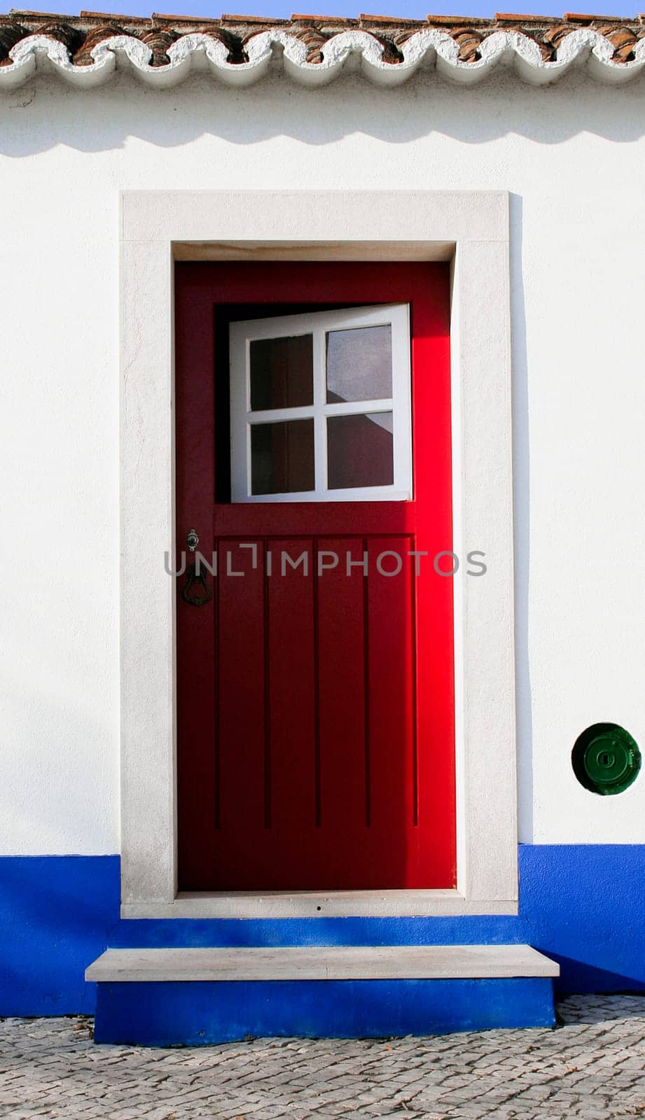 Tiny door painted with vivid colors at Vila Nova de Milfontes house. Little picturesque town on the Alentejo coast, Portugal