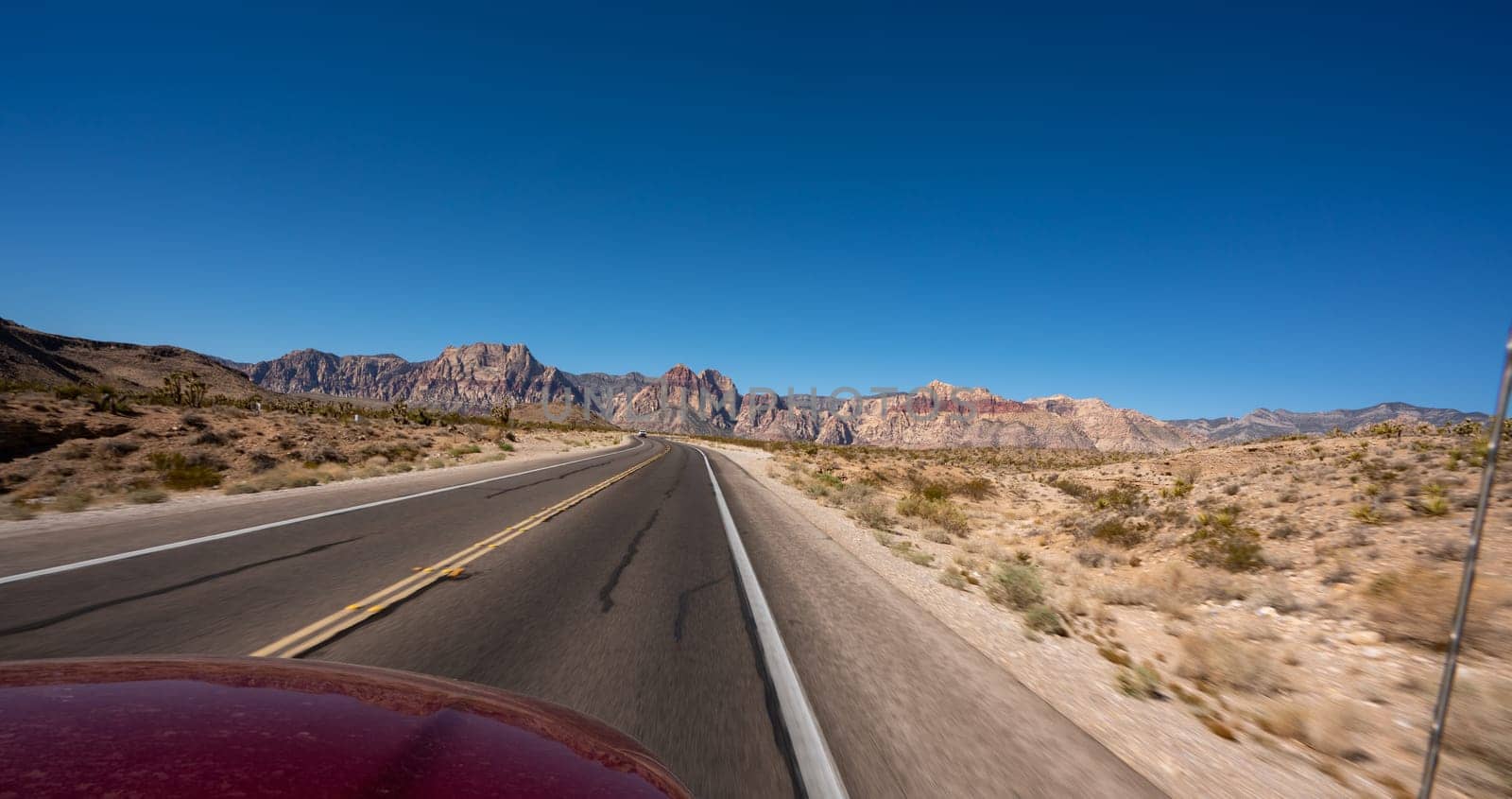 Empty long nevada mountain road to the horizon on a sunny summer day at bright sunset