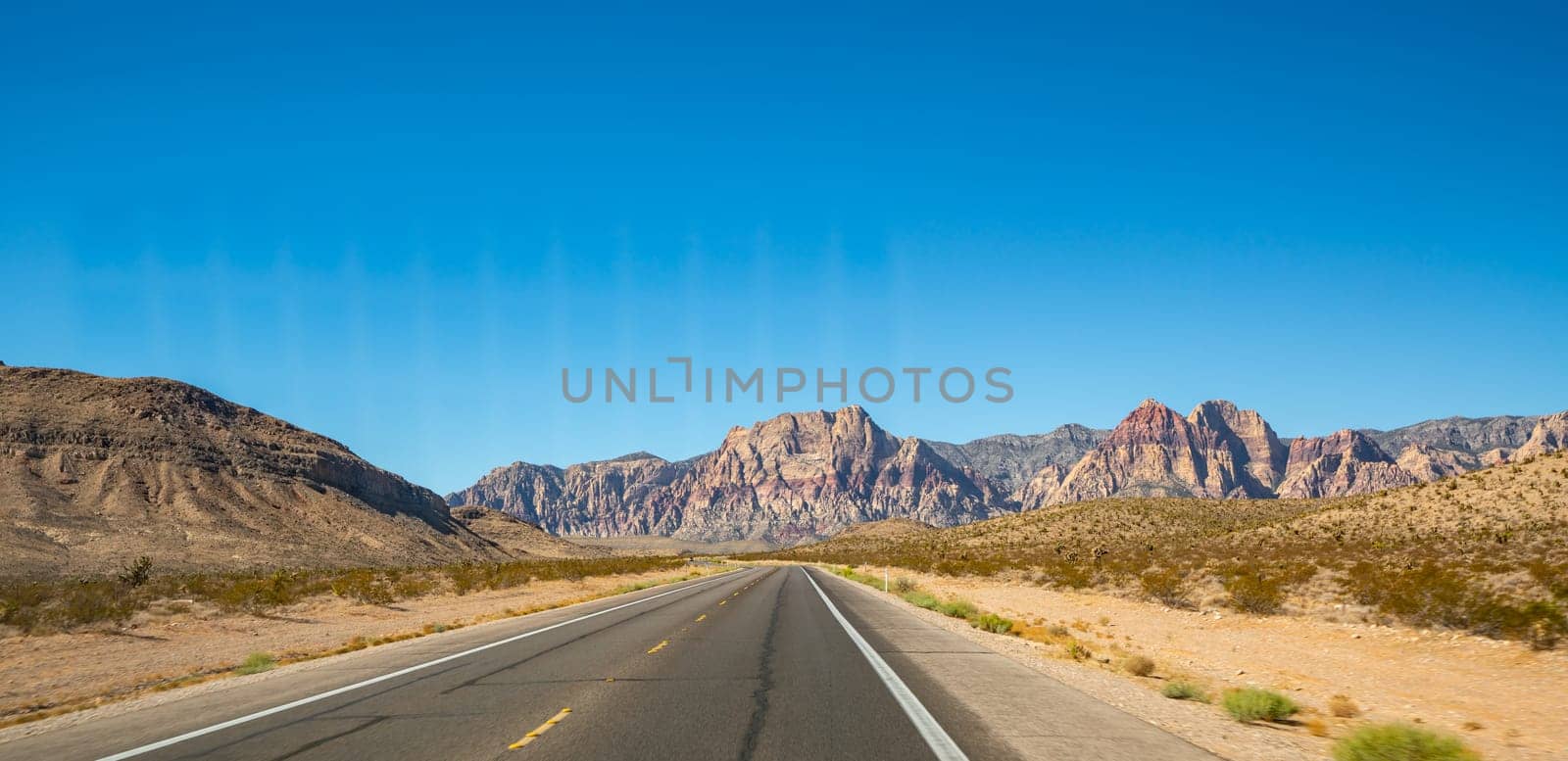 Empty long nevada mountain road to the horizon on a sunny summer day at bright sunset