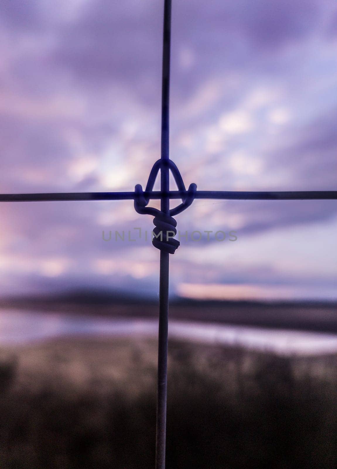 Metal fence cross lock knot at dawn. Reservoir at bottom