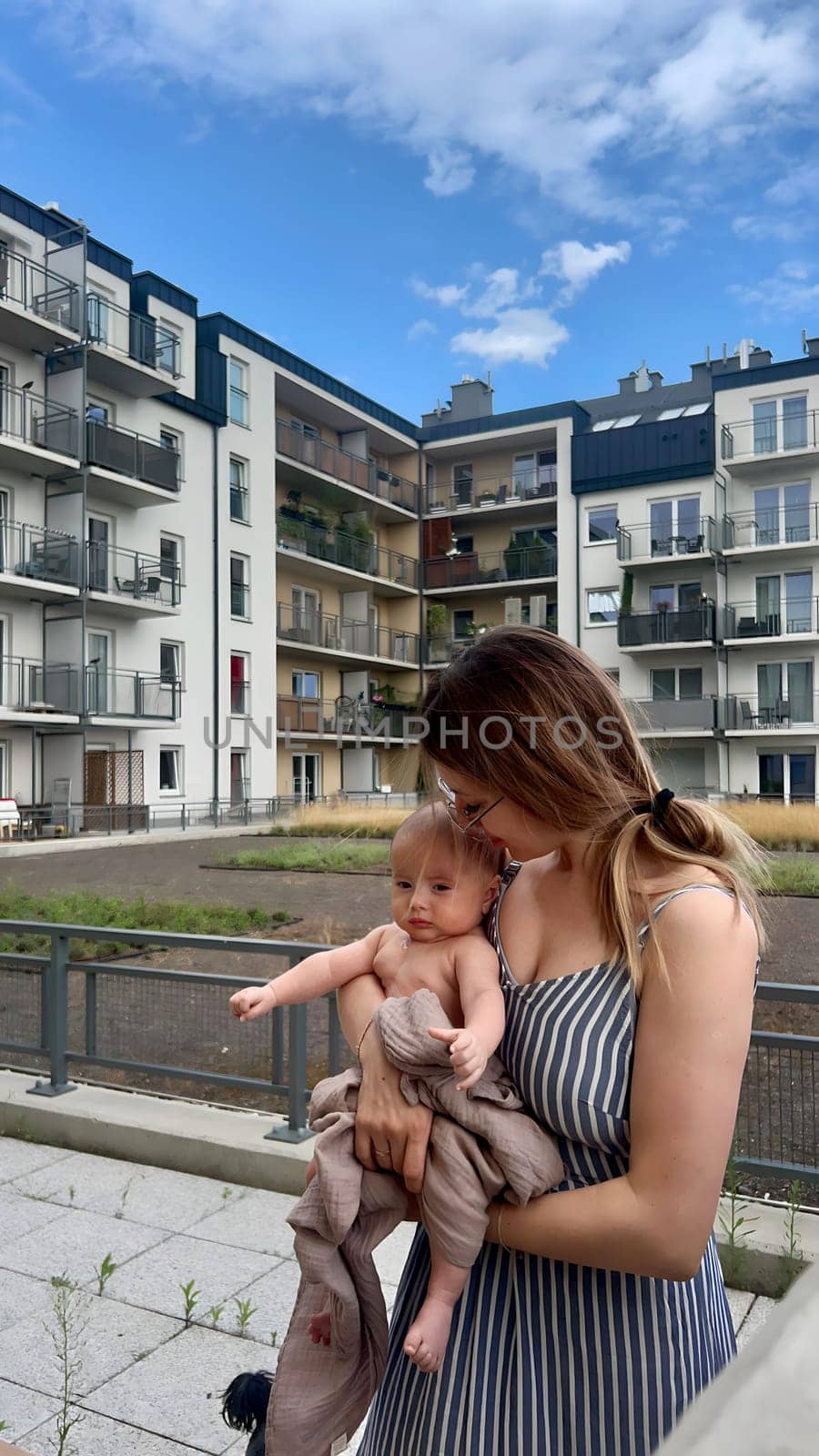 A young woman with a baby in her arms rests on the terrace.