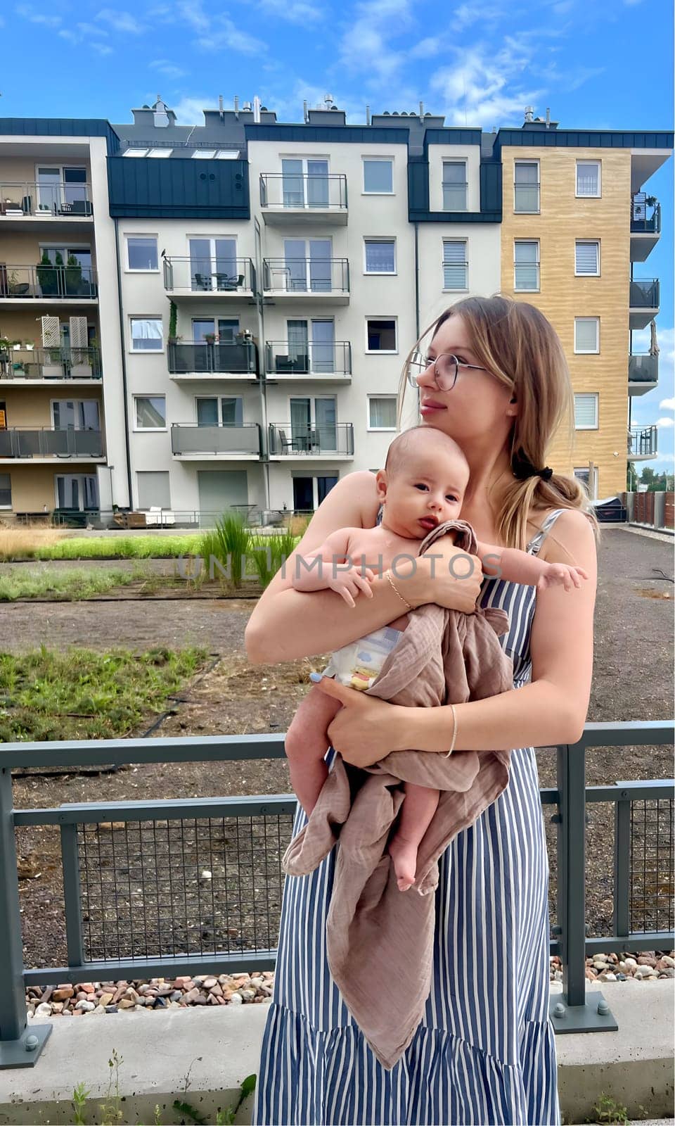 A young woman with a baby in her arms rests on the terrace.