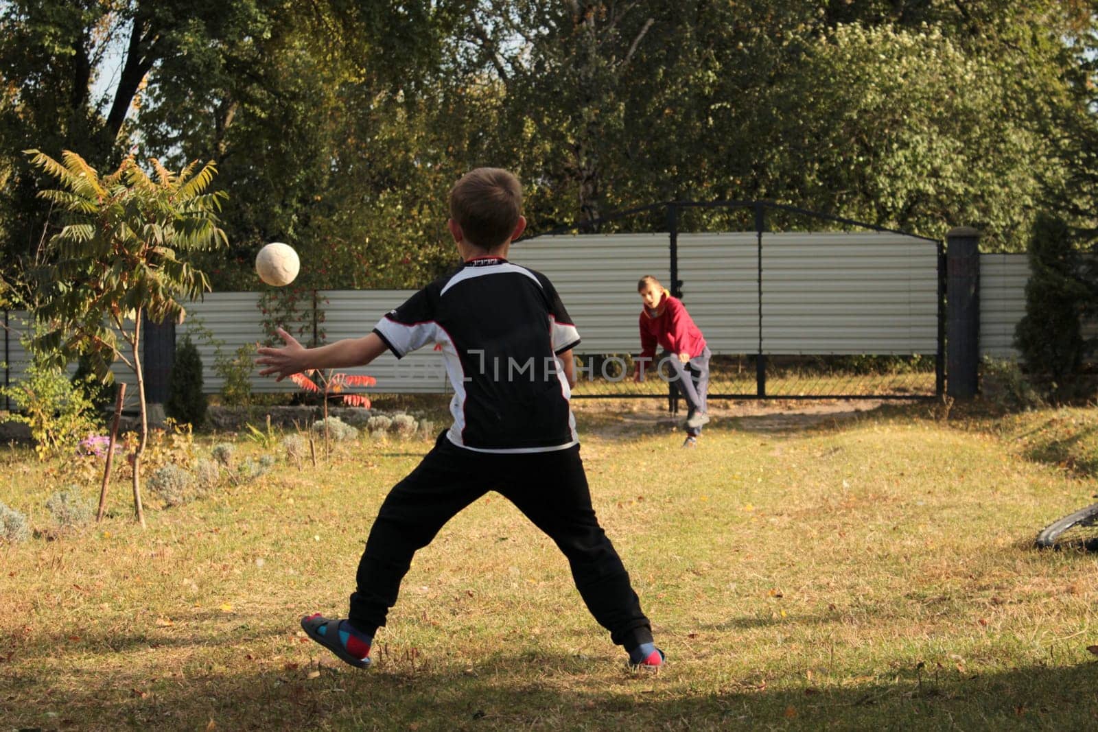 Two boys friends are playing ball in the backyard on summer vacation
