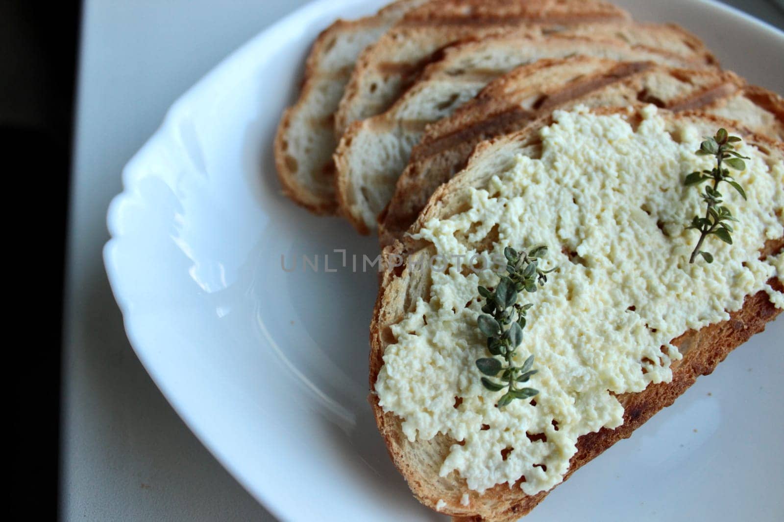 sandwiches from a loaf and with cheese paste on a wooden stand and in a white plate