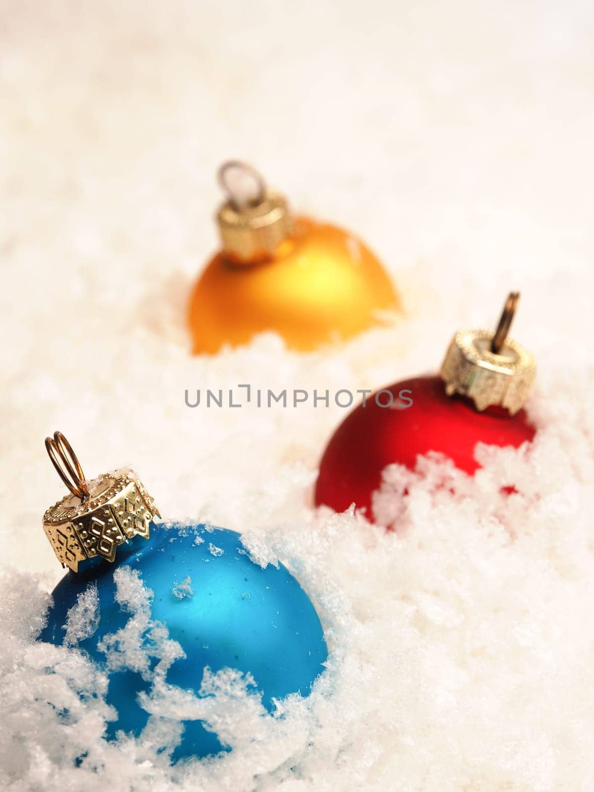 Three old vintage Christmas baubles in snow, seasonal table top with colorful Christmas balls