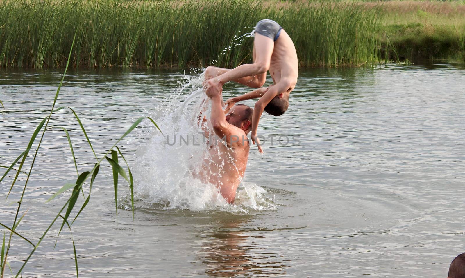 Father teaches his sons to swim and jump into the water, children having fun and having fun on the weekend by the river