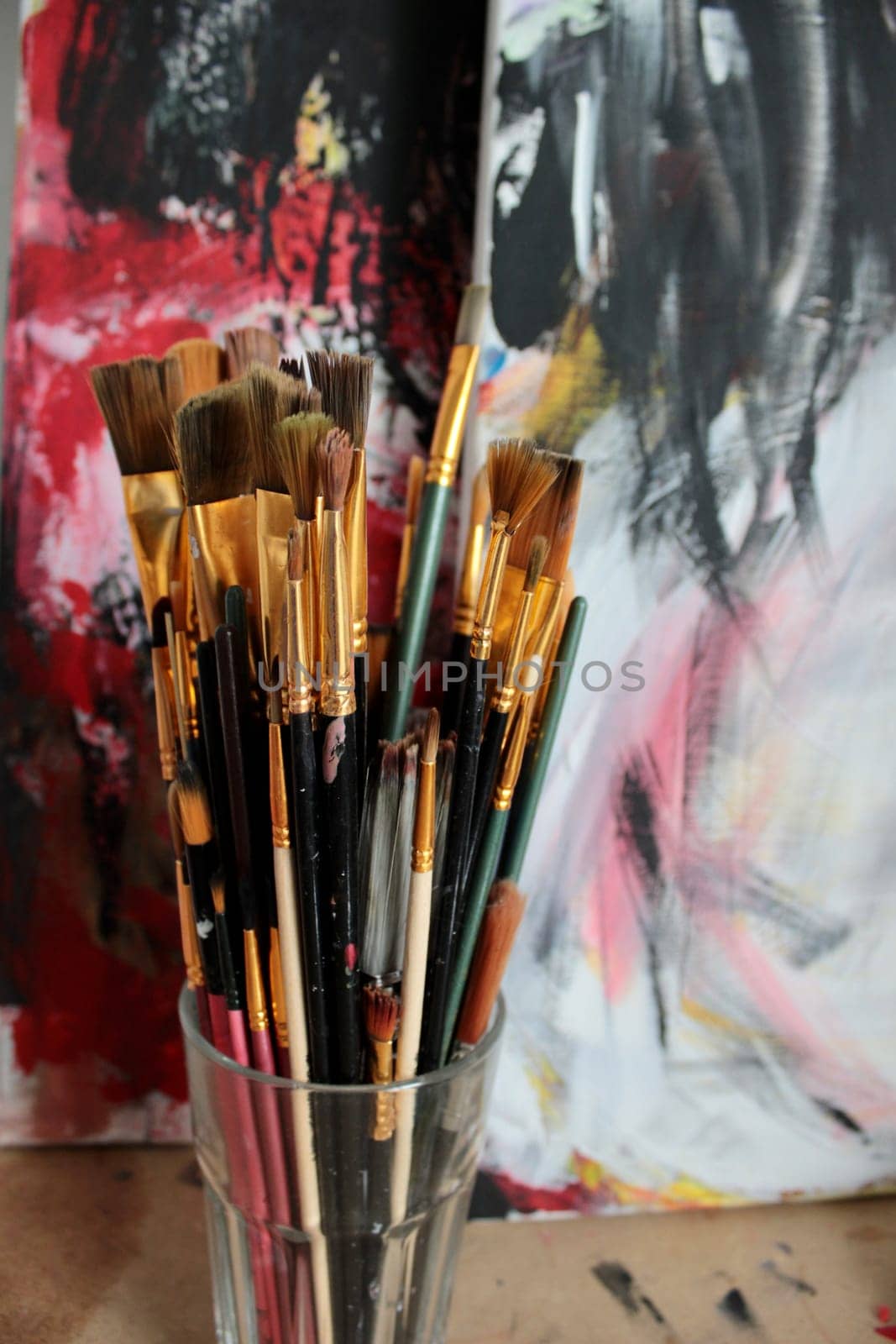 set of different brushes for painting at the workplace of the artist on the background of the painted picture